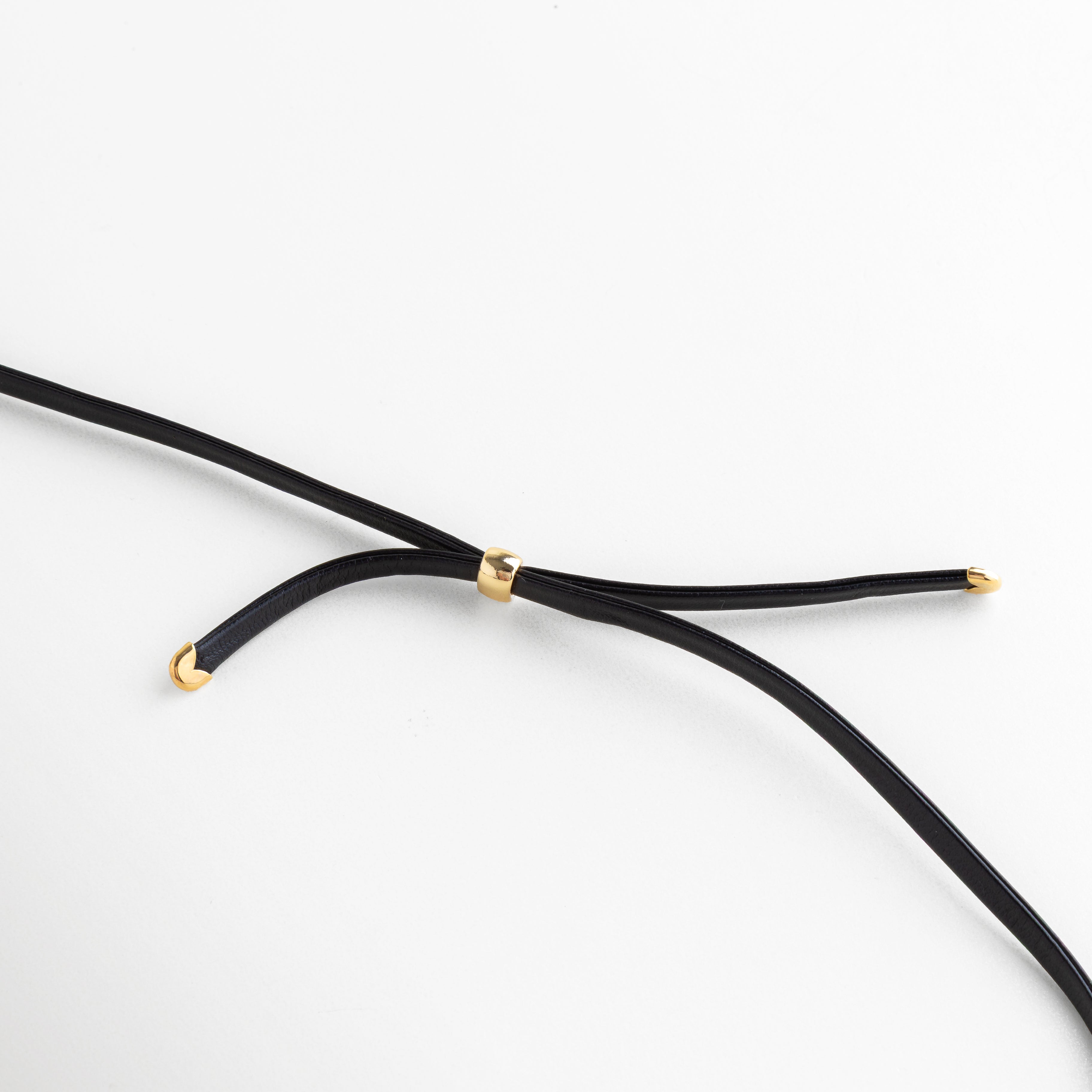 Primer plano del pasador dorado ajustable en el cordón de cuero del collar, Detalle de los terminales enchapados en oro en las puntas del cordón negro, Mecanismo de ajuste del collar Gold Monet con componentes de oro 18K, Zoom a los acabados de calidad en el cordón de cuero y herrajes dorados, Vista técnica del cierre y puntas del collar que muestra el baño de oro premium.