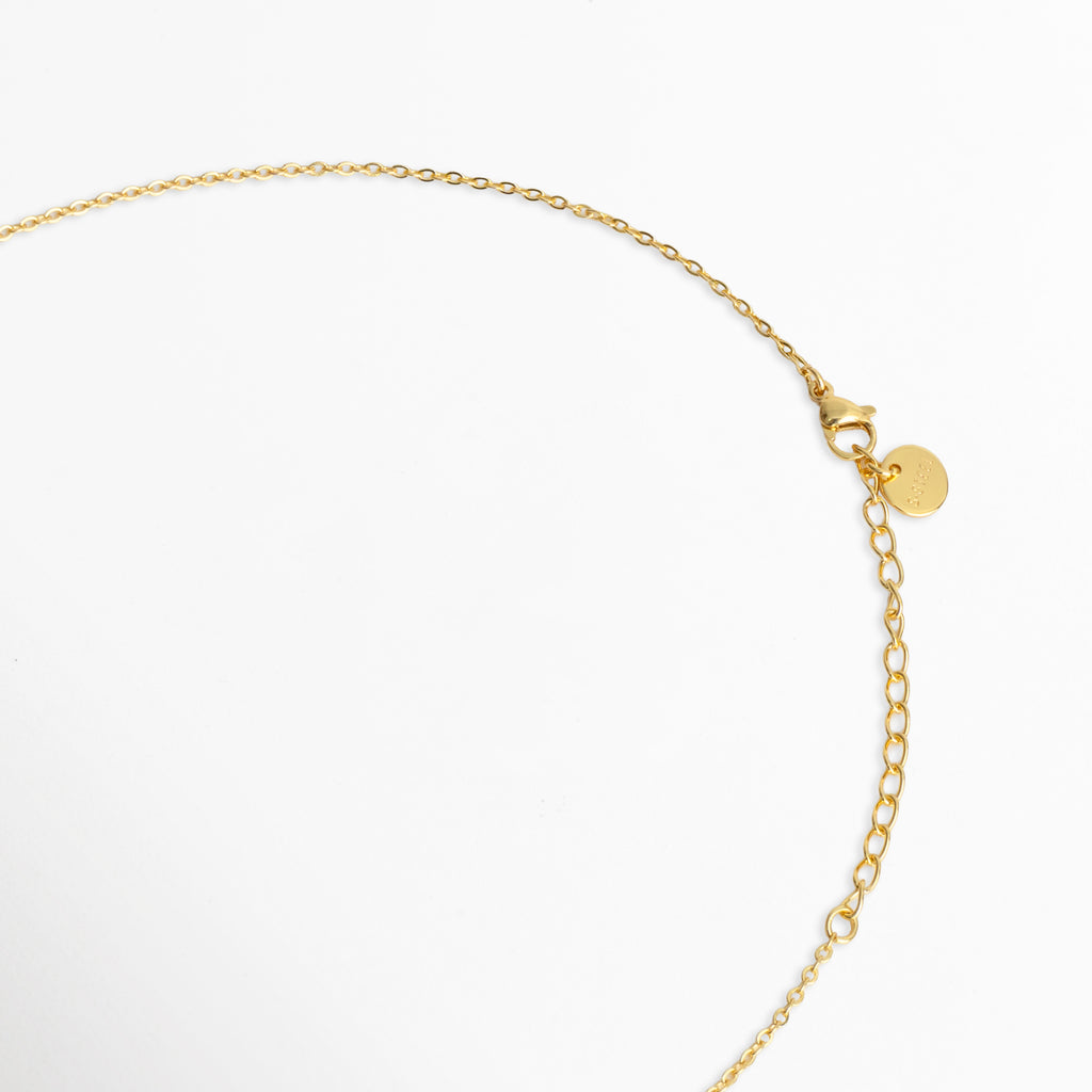 Detalle del cierre de broche de reasa/mosquetón con cadena de extensión de 5 cm y chapita distintiva de la marca en tono dorado, Vista de cerca del sistema de ajuste del Collar Prisma Dorado en enchapado de oro, Acercamiento a los eslabones finales y mecanismo de seguridad de la cadena dorada, Detalle de la terminación pulida de la extensión ajustable del collar Prisma Dorado.