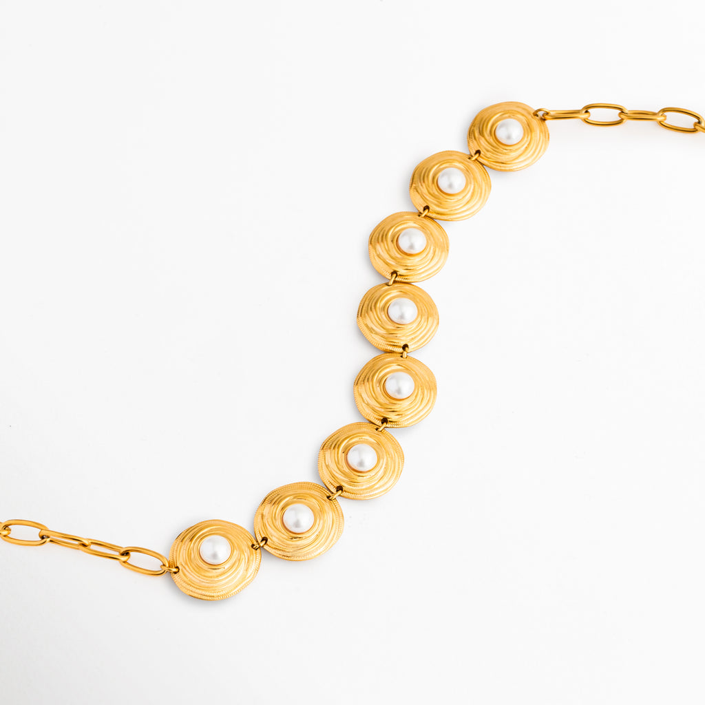 Detalle del Collar Khalira con perlas de alto brillo, Acercamiento a las perlas brillantes y acabado dorado elegante, Collar con incrustaciones de perla y diseño refinado, Detalle de joyería femenina con perlas y baño de Oro 18K, Perlas luminosas que aportan un toque sofisticado al collar.