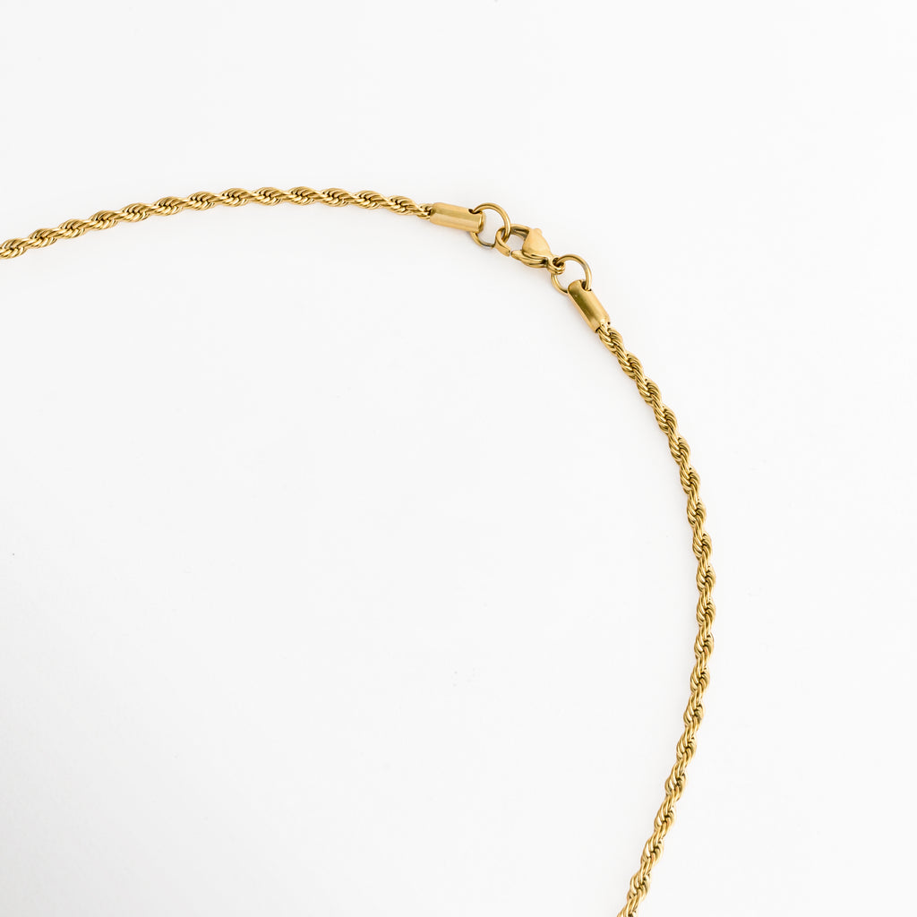 Acercamiento al broche de langosta o reasa en la cadena de cordón de 55 cm del Collar Padre Nuestro Bitono, Vista macro del sistema de cierre seguro en acabado dorado brillante sobre fondo blanco, Detalle del tejido tipo torzal de la cadena y la terminación del cierre enchapado en oro 18K, Muestra del mecanismo de sujeción metálico pulido de la cadena dorada.   