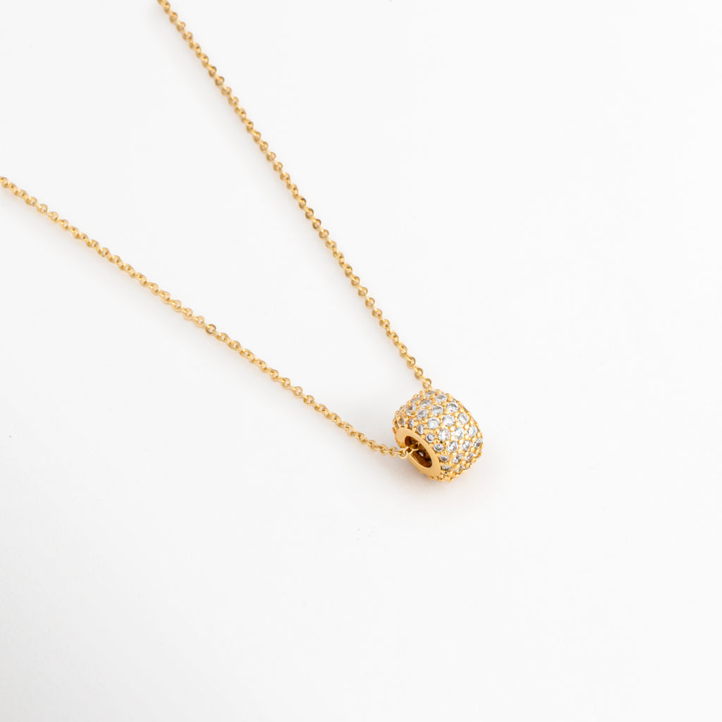 Acercamiento del dije rectangular del Collar Modi con zirconias y acabado en oro, Detalle del colgante rectangular con incrustaciones de zirconias del Collar Modi, Vista cercana del dije dorado del Collar Modi que muestra el brillo de las zirconias, Detalle del colgante rectangular enchapado en oro con zirconias del Collar Modi, Primer plano del dije del Collar Modi elaborado en cobre con recubrimiento en oro.