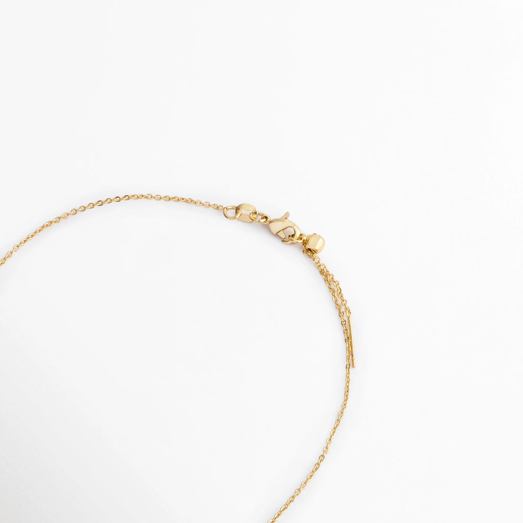 Vista del cierre y cadena del Collar Modi con acabado en oro, Detalle de la cadena fina y broche del Collar Modi elaborado en cobre, Acercamiento del sistema de cierre del Collar Modi con recubrimiento en oro, Vista parcial de la cadena del Collar Modi con acabado dorado y cierre de broche, Detalle del collar Modi que muestra la cadena fina y el cierre metálico.