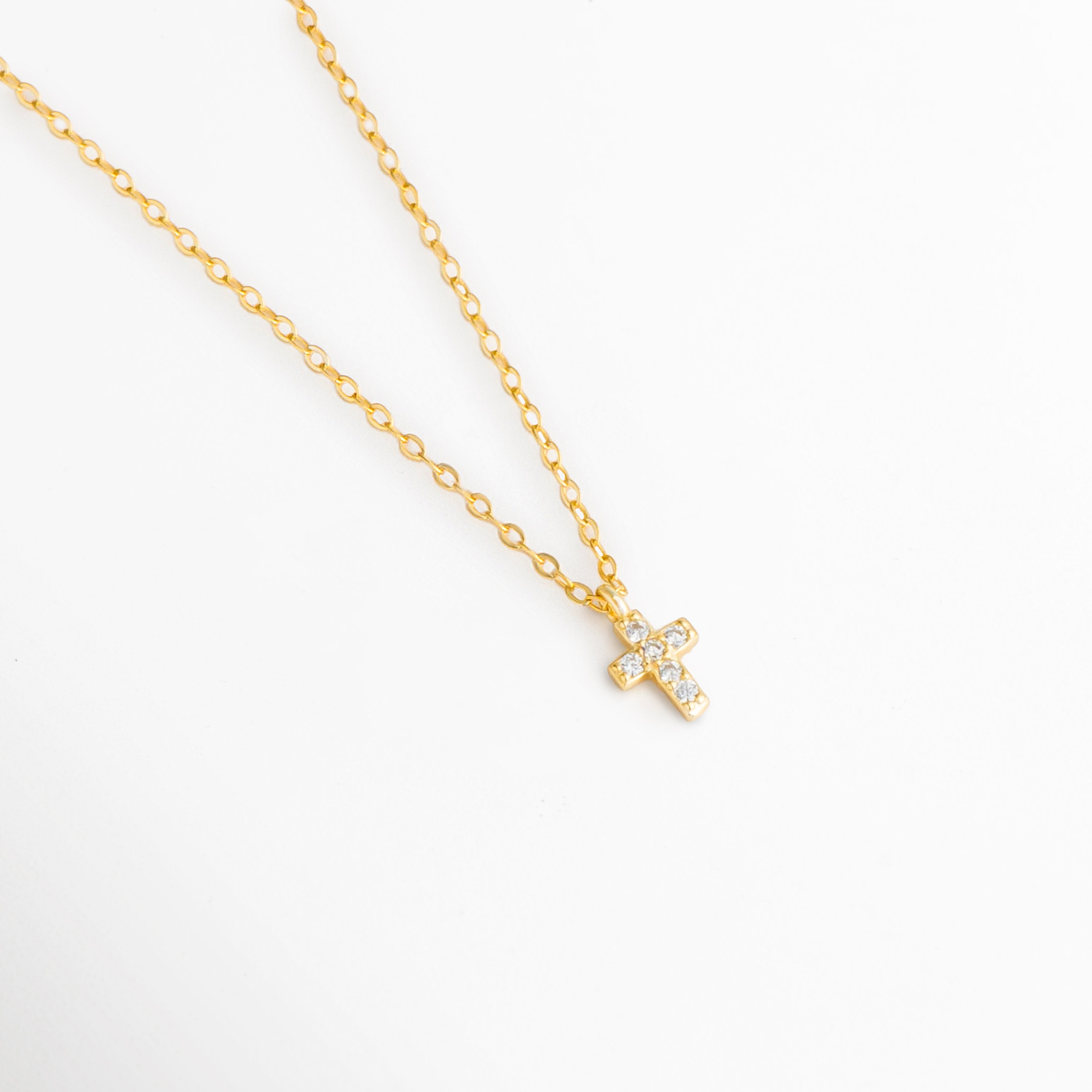 Detalle del Collar Gloria con cruz mini incrustada con zirconias, Vista cercana del dije de cruz dorada con acabado en oro 14K, Collar con colgante religioso de zirconias y brillo sutil, Acercamiento a la cruz mini del Collar Gloria en plata ley 925, Detalle de joyería fina con cruz de zirconias y diseño delicado.