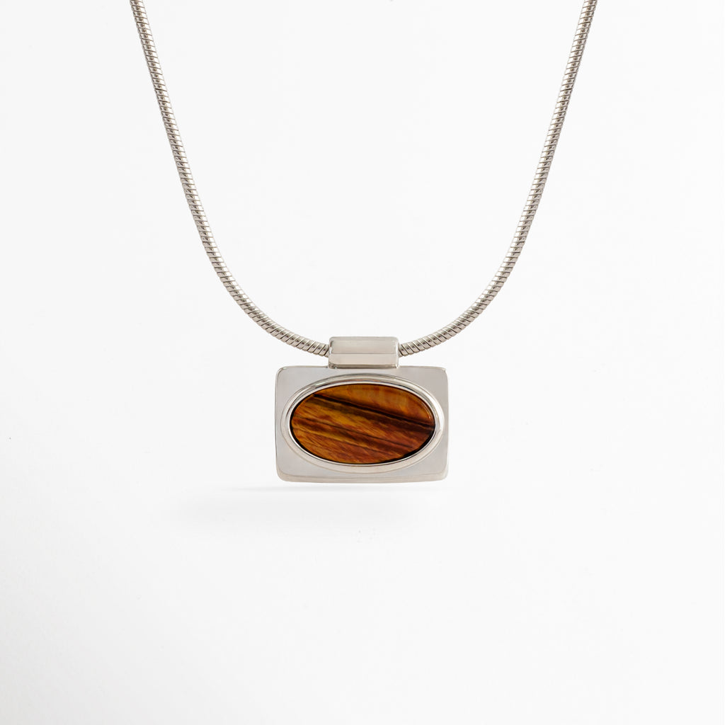 Collar Tigra con colgante rectangular de piedra tipo Ojo de Tigre y cadena con acabado en Oro Blanco sobre fondo blanco, Vista frontal del Collar Tigra con dije de piedra tipo Ojo de Tigre y cadena de cobre con recubrimiento en Oro Blanco, Collar Tigra con colgante de piedra Ojo de Tigre en diseño minimalista y acabado en Oro Blanco, Collar de mujer Tigra con dije rectangular de piedra Ojo de Tigre y cadena fina en acabado Oro Blanco, Collar Tigra elaborado en cobre con recubrimiento en Oro Blanco