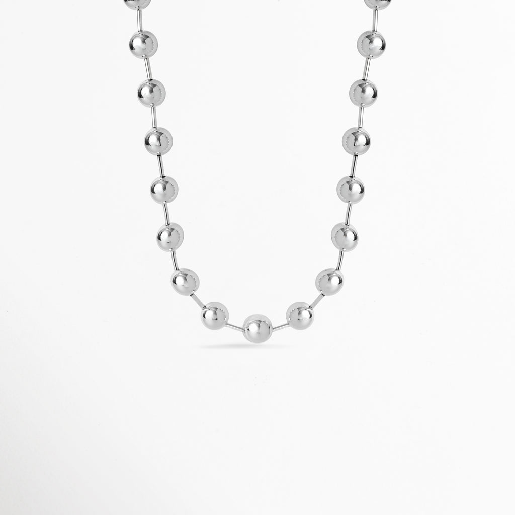 Collar Selene de latón enchapado en oro blanco 24k de 46 cm de largo compuesto por esferas metálicas espaciadas, vista frontal sobre fondo blanco, Vista de frente de collar plateado estilo esfera o esférico de 1.2 cm de ancho suspendido en una fina cadena, Plano general de collar plateado de diseño esférico minimalista enchapado en oro blanco 24k sobre fondo neutro, Collar Selene destacando el acabado pulido espejo de sus esferas metálicas flotantes y su brillo