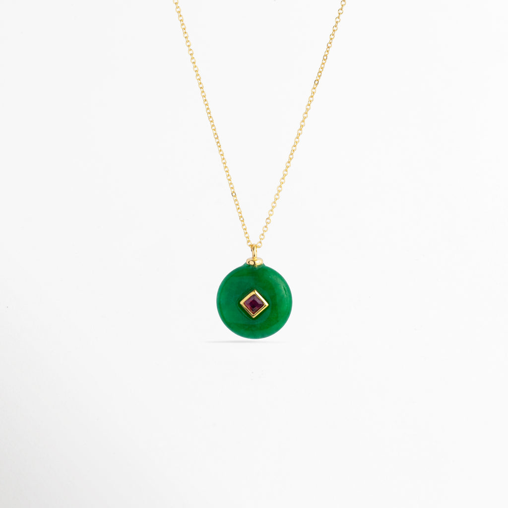 Collar Ela con dije circular de piedra natural verde esmeralda e incrustación central en rombo de zirconia fucsia o rubí enchapado en oro 18K, vista frontal sobre fondo blanco, Vista de frente de collar enchapado en oro 18K con dije de disco verde estilo dona de piedra natural y gema central cuadrada en bisel dorado, Collar elegante de cadena fina con dije medallón circular verde y piedra de zirconia roja/fucsia en el centro, Gargantilla dorada con dije de piedra
