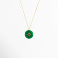 Collar Ela con dije circular de piedra natural verde esmeralda e incrustación central en rombo de zirconia fucsia o rubí enchapado en oro 18K, vista frontal sobre fondo blanco, Vista de frente de collar enchapado en oro 18K con dije de disco verde estilo dona de piedra natural y gema central cuadrada en bisel dorado, Collar elegante de cadena fina con dije medallón circular verde y piedra de zirconia roja/fucsia en el centro, Gargantilla dorada con dije de piedra