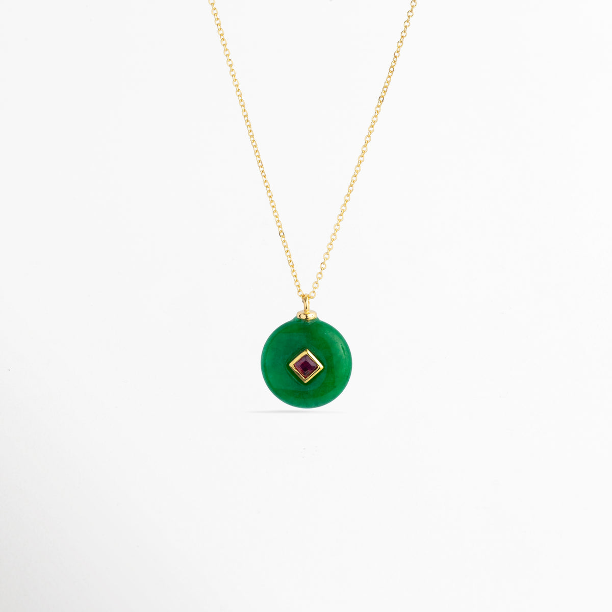 Collar Ela con dije circular de piedra natural verde esmeralda e incrustación central en rombo de zirconia fucsia o rubí enchapado en oro 18K, vista frontal sobre fondo blanco, Vista de frente de collar enchapado en oro 18K con dije de disco verde estilo dona de piedra natural y gema central cuadrada en bisel dorado, Collar elegante de cadena fina con dije medallón circular verde y piedra de zirconia roja/fucsia en el centro, Gargantilla dorada con dije de piedra