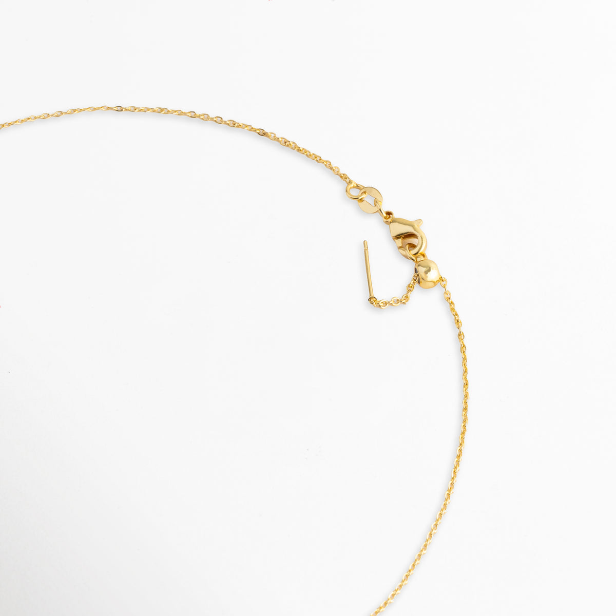 Vista del broche de reasa o langosta con cadena de extensión ajustable de 6 cm enchapada en oro 18K, Detalle del sistema de cierre seguro y la terminación de la cadena del Collar Ela sobre fondo blanco, Acercamiento al broche y eslabones de ajuste de 44 cm a 50 cm de la cadena enchapada en oro, Muestra del acabado pulido del cierre metálico y la delicada placa de la marca.