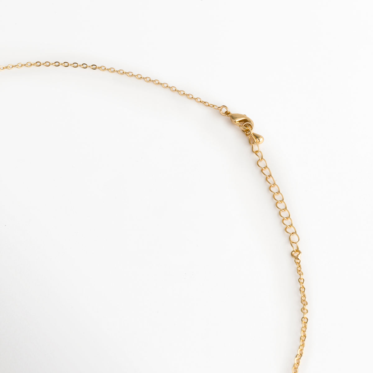 Acercamiento al broche de reasa y la cadena de extensión de 5 cm del Collar Grapa, Vista macro del sistema de ajuste y cierre seguro en acabado dorado brillante sobre fondo blanco, Detalle de los eslabones de extensión que permiten adaptar la cadena de 40 cm a 45 cm, Muestra del mecanismo de sujeción metálico pulido enchapado en oro 18K.