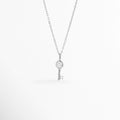 Collar Silver Kael de plata ley 925 enchapado en oro blanco 14K con dije de llave minimalista y circonia central incrustada, vista de frente sobre fondo blanco, Vista frontal de collar plateado con dije de llave de 1.6 cm con pedrería brillante engastada en el cabezal y la punta, Plano general de collar fino de plata ley 925 enchapado en oro blanco 14K con dije de llave delicada sobre cadena de 45 cm, Collar Silver Kael destacando los destellos de las circonias