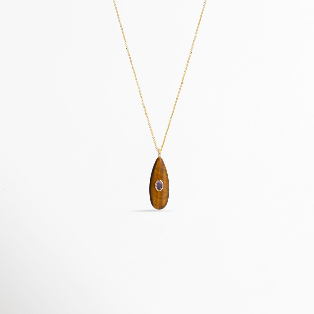 Collar Cuarzo Toffee de cobre enchapado en oro con dije de piedra natural ojo de tigre en forma de gota alargada e incrustación central violeta, vista frontal sobre fondo blanco, Vista de frente de collar dorado con dije de cuarzo tono café toffee de 4 cm de largo y pequeño cristal ovalado incrustado al centro, Plano general de collar fino con dije orgánico en forma de lágrima en piedra natural veteada tono toffee sobre fondo neutro.