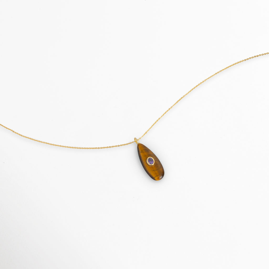 Vista aérea en curva suave del Collar Cuarzo Toffee con el dije de gota toffee reposando sobre fondo blanco, Toma extendida de la fina cadena dorada mostrando la soltura y proporción del dije de , piedra natural de 4 cmMuestra de las vetas cálidas tono toffee y la piedra acentuada al centro en ángulo horizontal,  Acercamiento al flujo sutil de la cadena enchapada en oro de 45 cm de longitud. 
