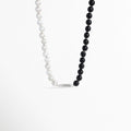Collar Black & White con diseño divido entre esferas de madera de ébano negra y perlas blancas, unido por una barrita metálica central, vista de frente sobre fondo blanco, Vista de frente de collar duotono de 40 cm de largo y 1 cm de ancho, combinando cuentas negras mate de ébano sintético y cuentas perla satinadas, Plano general de collar bicolor de estilo orgánico y contemporáneo con conector metálico en la base sobre fondo neutro, Collar Black & White destacando 