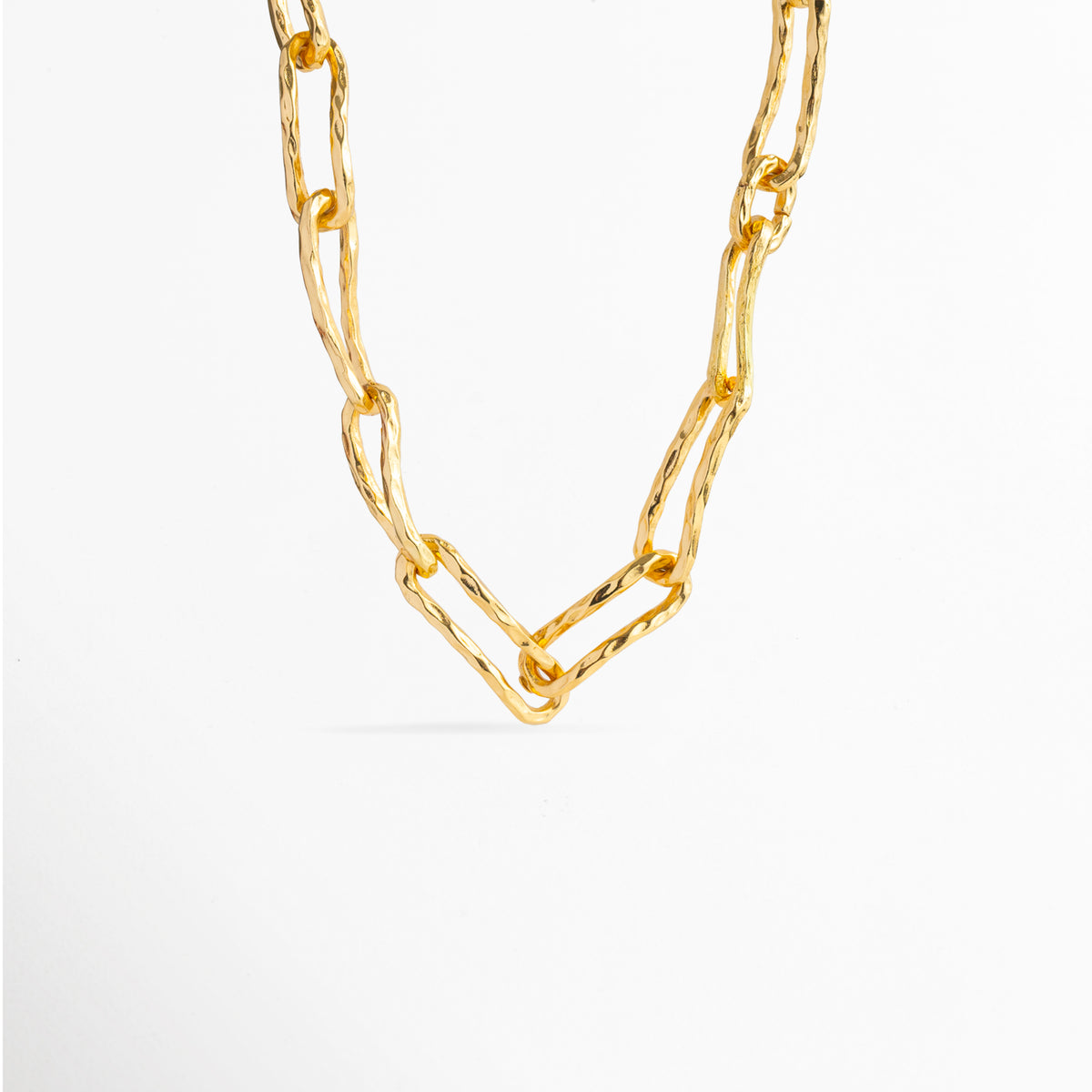 Collar Golden Marah de cobre enchapado en oro con eslabones rectangulares orgánicos y textura martillada artesanal, vista frontal sobre fondo blanco, Vista de frente de collar grueso dorado de 1.5 cm de ancho con eslabones de silueta irregular y acabado de relieve rustico, Plano general de cadena gruesa de eslabones alargados con superficie texturizada enchapada en oro, Collar Golden Marah destacando el brillo cálido del baño de oro y la forma escultórica