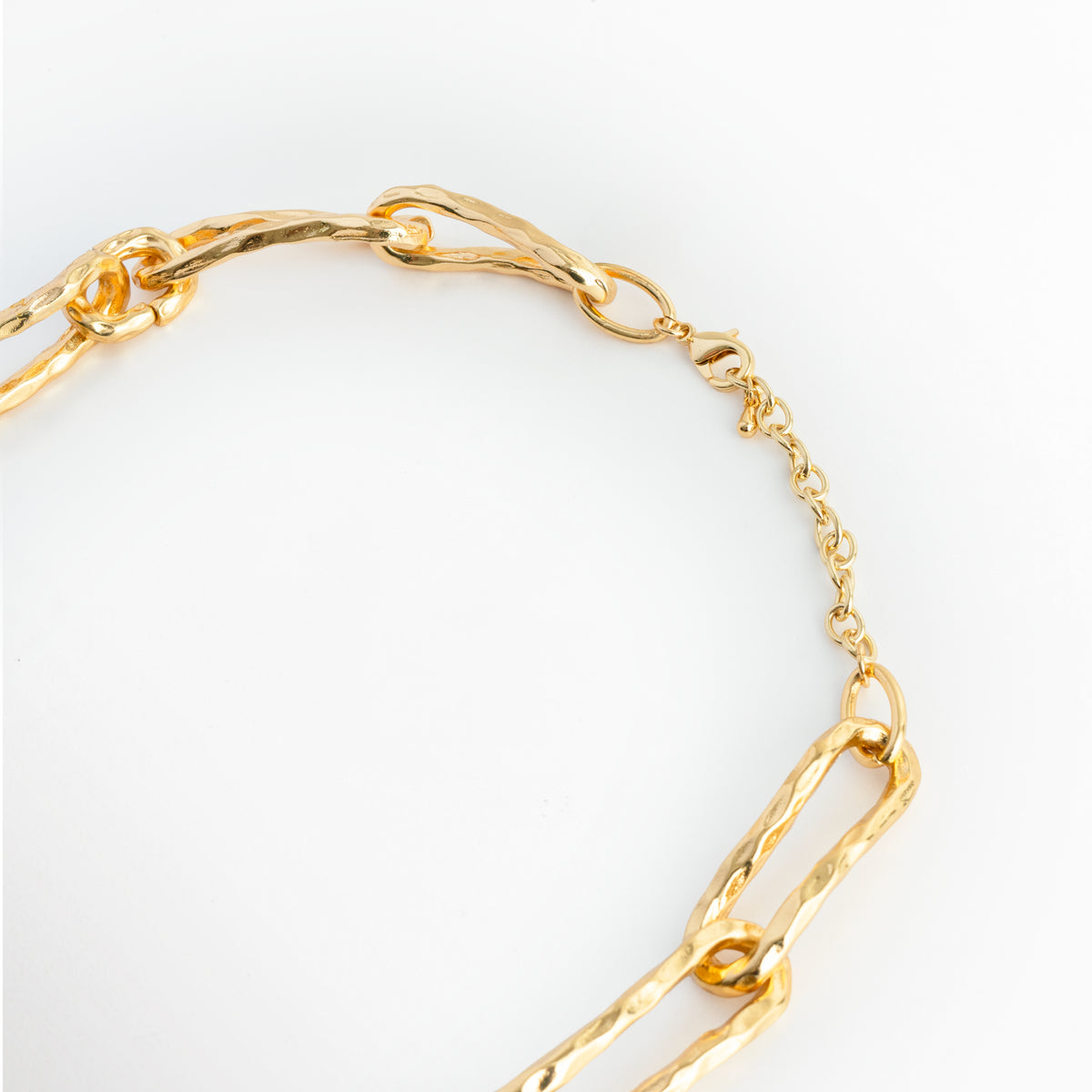 Acercamiento al broche de mosquetón y la cadena de extensión de 7 cm enchapada en oro del Collar Golden Marah, Vista macro del sistema de sujeción ajustable y la terminación pulida sobre fondo blanco, Detalle de los eslabones de extensión que permiten adaptar la cadena de 47 cm a 54 cm de longitud tota, Muestra del mecanismo de cierre metálico seguro y duradero en tono oro brillante.