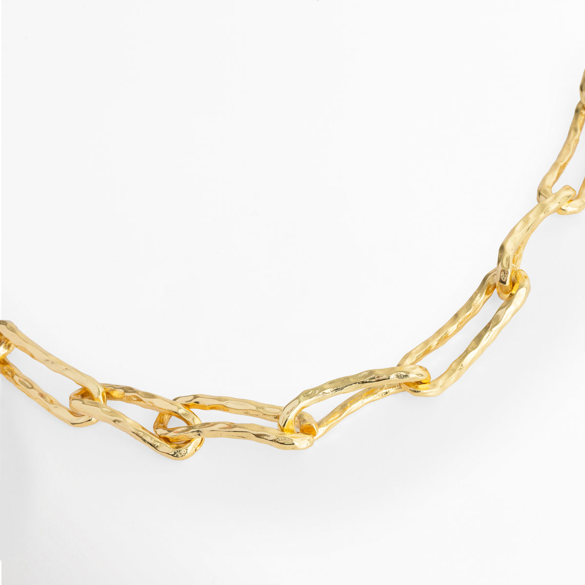 Vista horizontal en curva suave del Collar Golden Marah mostrando la continuidad de sus eslabones martillados, Acercamiento a la textura artesanal y al grosor de 1.5 cm de la cadena de eslabones orgánicos, Toma en diagonal que resalta los destellos de luz sobre las imperfecciones calculadas del acabado dorado, Muestra del diseño fluido y la caída natural de los eslabones rectangulares enchapados en oro.