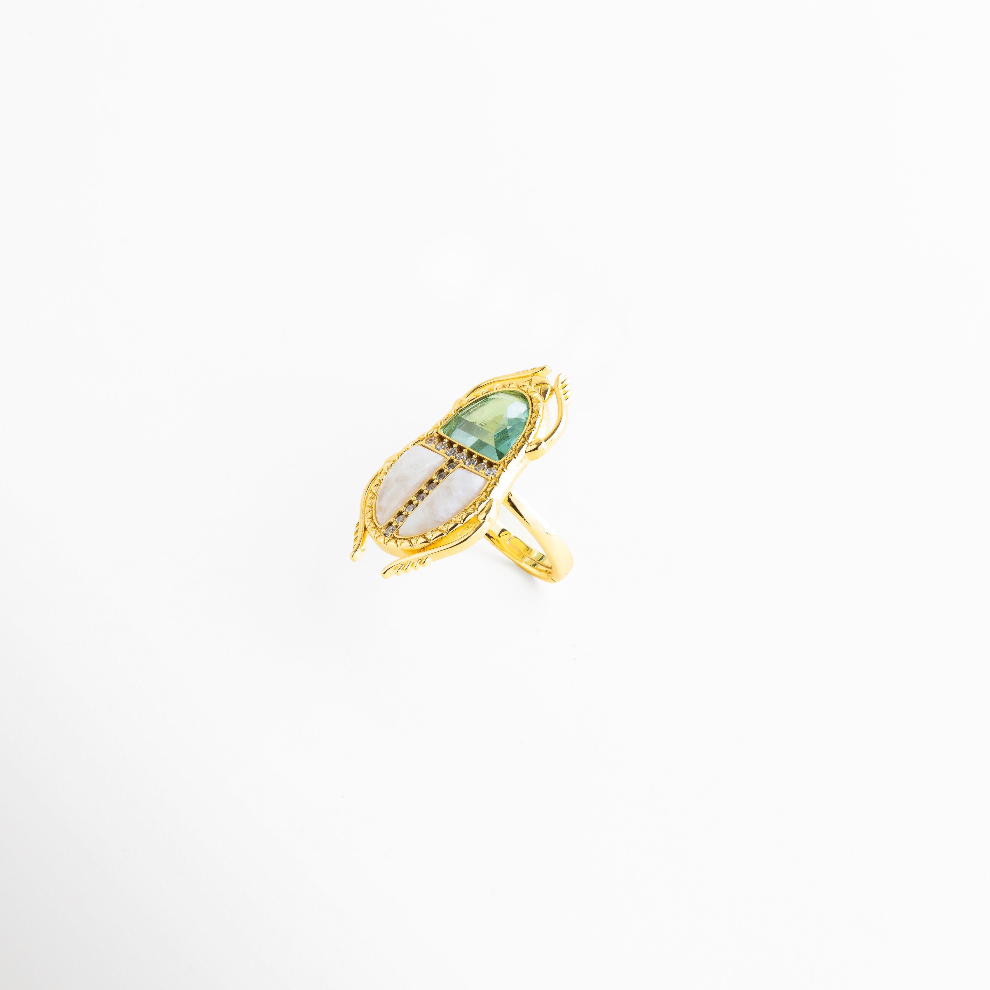 Detalle de cristales de color y zirconias en anillo dorado elegante, Primer plano de piedra central verde con zirconias en anillo ajustable, Acercamiento de cristales brillantes en anillo enchapado en oro 18K, Detalle de incrustaciones en anillo dorado con diseño tipo escarabajo, Cristales y zirconias en anillo elegante con acabado fino dorado