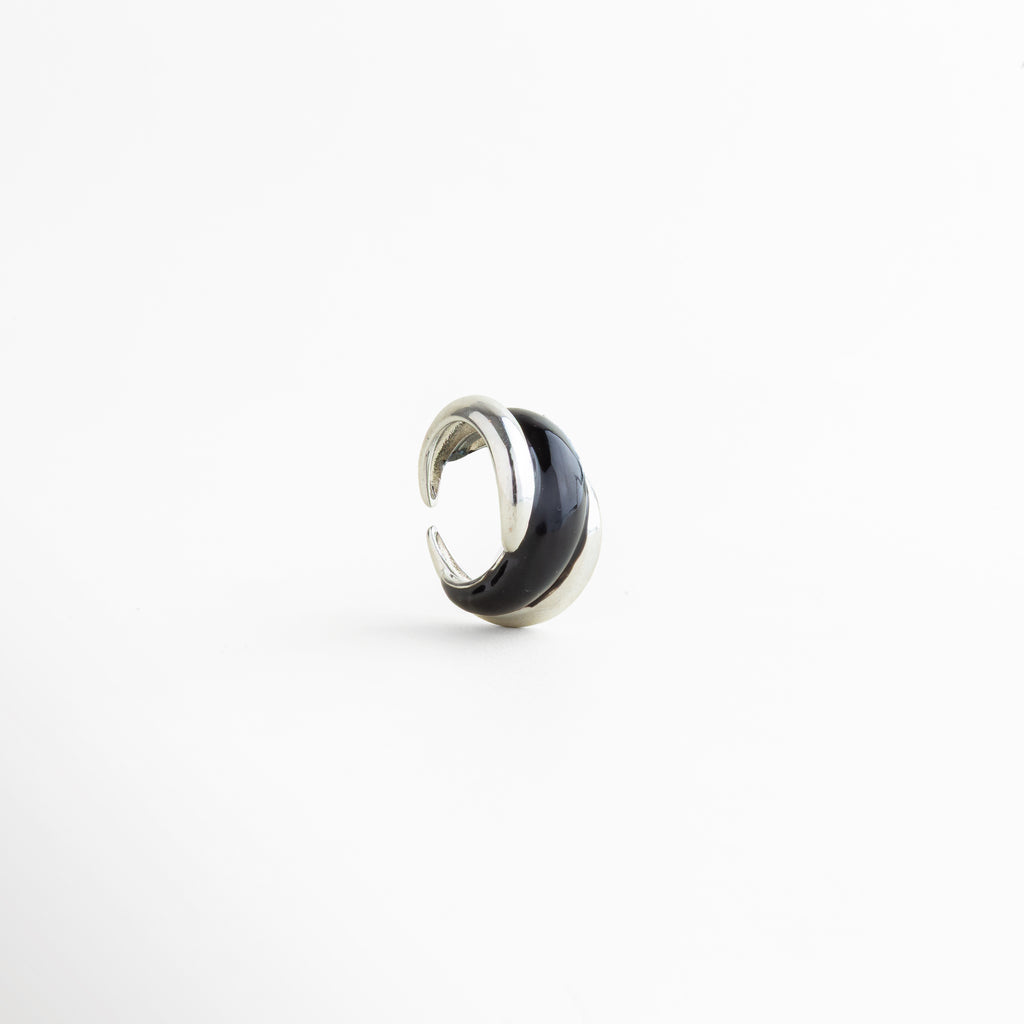Vista inclinada del Anillo Nerisse con diseño orgánico y acabado plateado brillante, Anillo moderno en tono plata visto en ángulo con forma envolvente y elegante, Vista diagonal de anillo statement con silueta curva y estilo contemporáneo, Anillo femenino con diseño audaz y acabado en Oro Blanco visto en perspectiva, Detalle angular del Anillo Nerisse con líneas suaves y apariencia sofisticada.