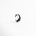 Vista inclinada del Anillo Nerisse con diseño orgánico y acabado plateado brillante, Anillo moderno en tono plata visto en ángulo con forma envolvente y elegante, Vista diagonal de anillo statement con silueta curva y estilo contemporáneo, Anillo femenino con diseño audaz y acabado en Oro Blanco visto en perspectiva, Detalle angular del Anillo Nerisse con líneas suaves y apariencia sofisticada.