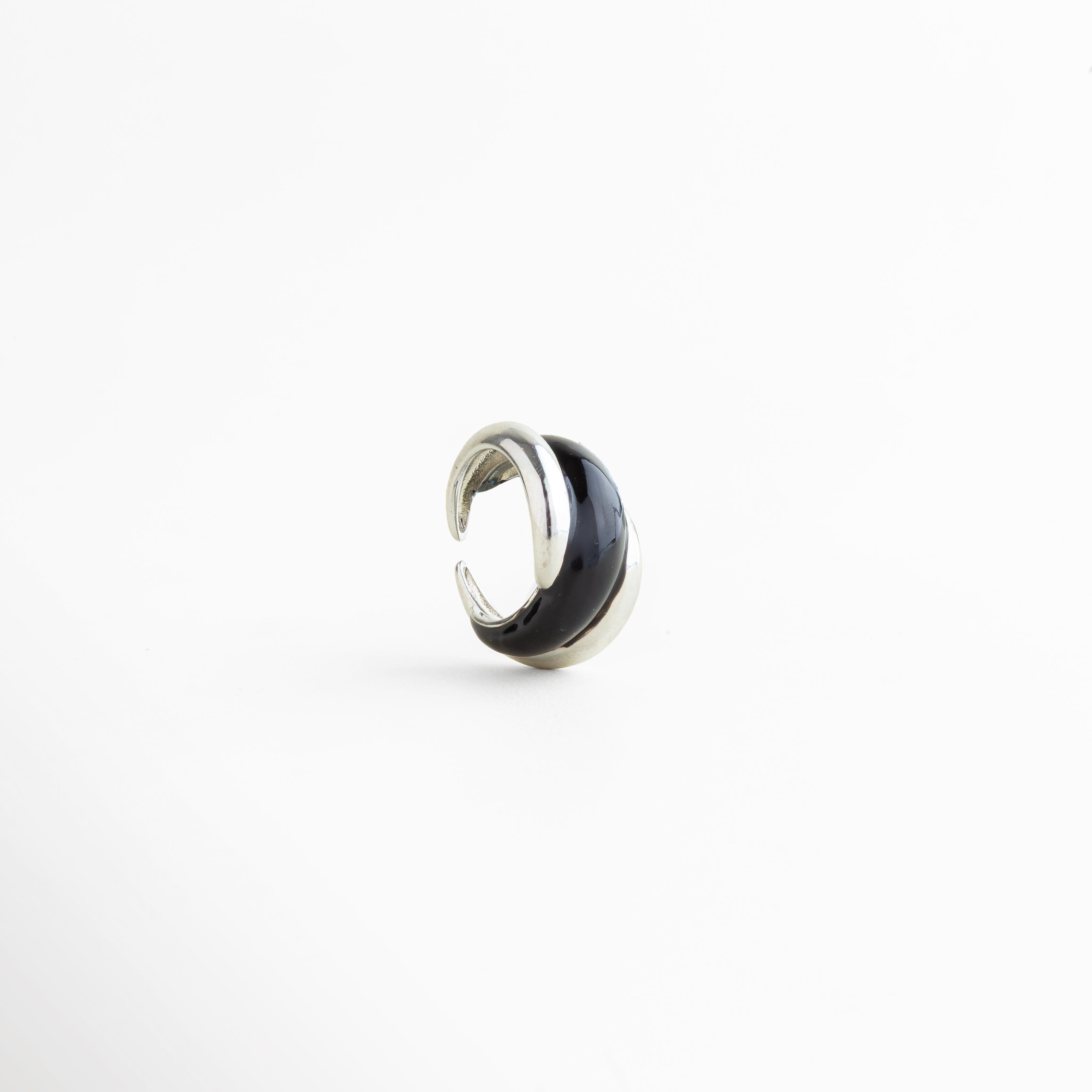 Vista inclinada del Anillo Nerisse con diseño orgánico y acabado plateado brillante, Anillo moderno en tono plata visto en ángulo con forma envolvente y elegante, Vista diagonal de anillo statement con silueta curva y estilo contemporáneo, Anillo femenino con diseño audaz y acabado en Oro Blanco visto en perspectiva, Detalle angular del Anillo Nerisse con líneas suaves y apariencia sofisticada.