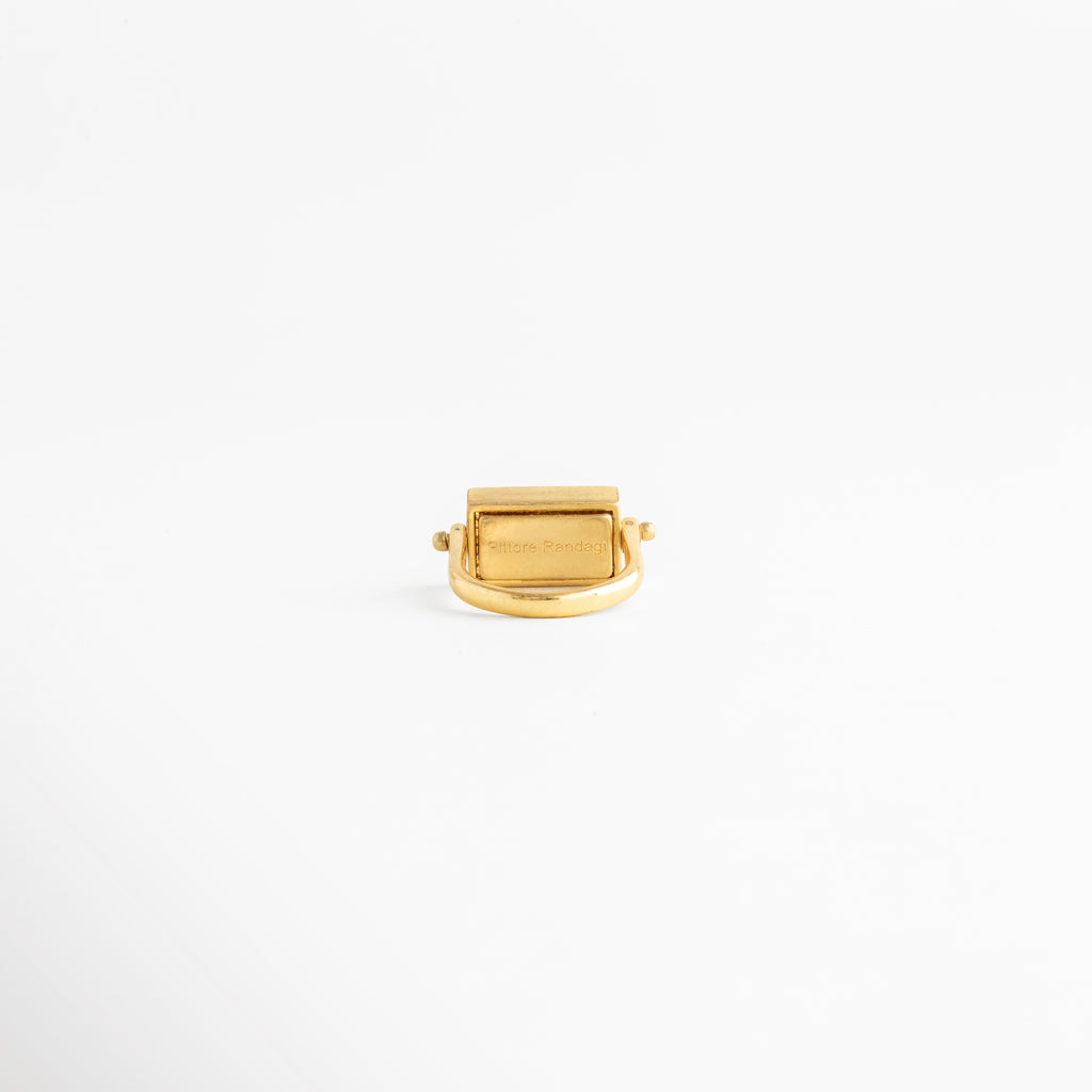 Vista trasera del anillo rectangular dorado mostrando el acabado interno y la unión de la banda, Detalle del reverso de la montura de piedra natural en anillo con baño de oro 18K, Parte interna de anillo de cobre enchapado en oro resaltando el trabajo de pulido artesanal, Perspectiva posterior de anillo minimalista que muestra la estabilidad del dije rectangular, Acabado interior de joya fina: anillo dorado con piedra café visto desde la base de la banda.