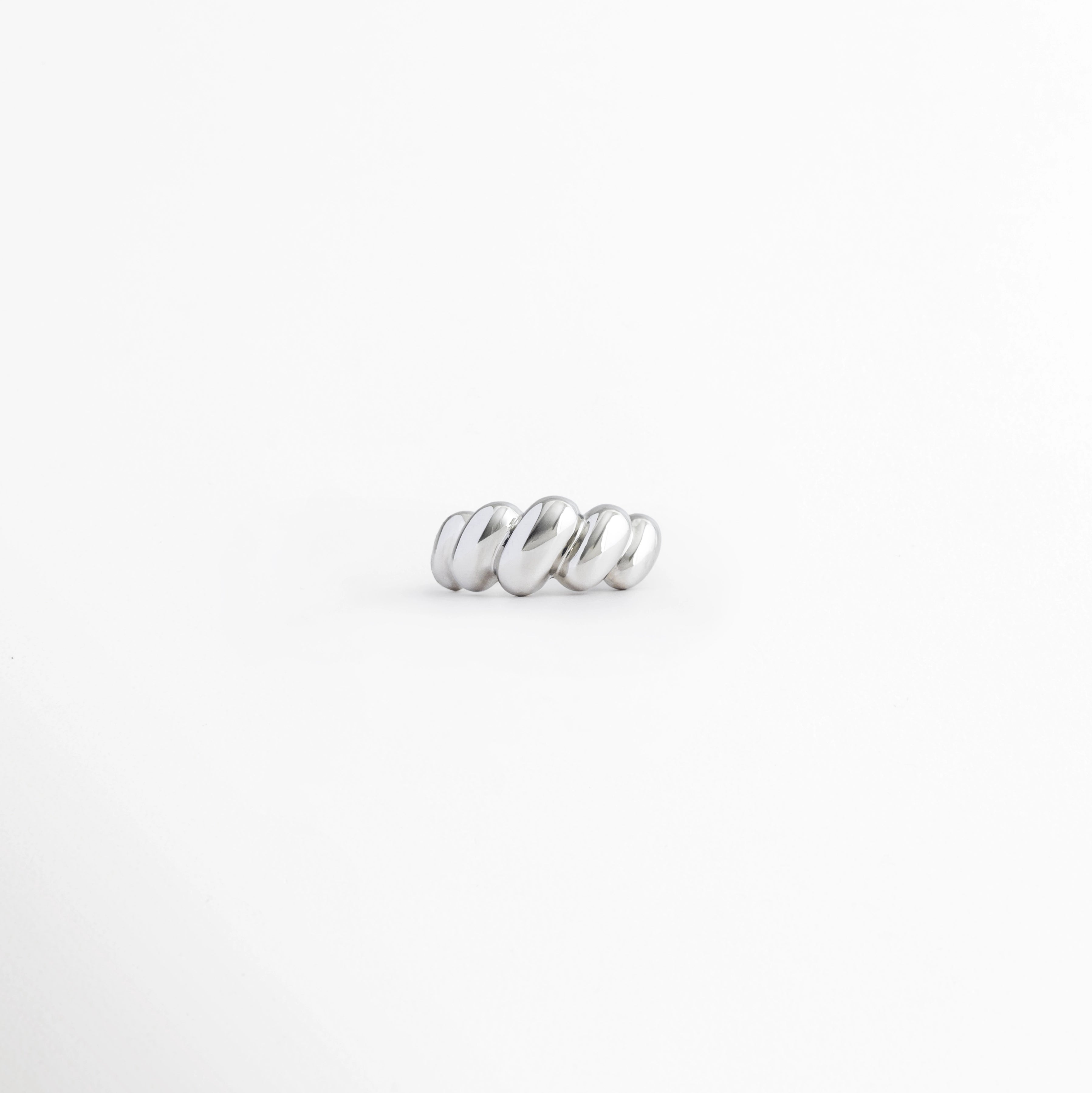 Anillo Virella de cobre con acabado plateado de pulido brillante y diseño entrelazado sobre fondo b, Vista frontal del Anillo Virella con diseño geométrico de bandas entrelazadas y acabado brillante, Anillo Virella con diseño moderno de aros entrecruzados y acabado plateado, Anillo Virella ajustable de cobre con acabado pulido brillante y estilo contemporáneo, Anillo plateado Virella con diseño entrelazado de líneas curvas y acabado brillante.