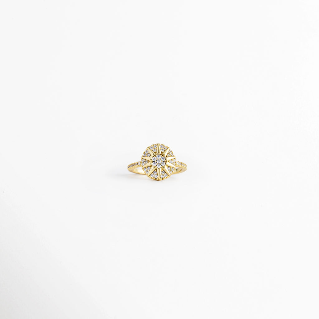 Anillo Elian ajustable de cobre con recubrimiento metálico e incrustaciones de zirconia, diseño floral, vista frontal, Anillo Elian con flor de zirconias y acabado dorado, vista frontal sobre fondo blanco, Vista frontal del Anillo Elian con diseño de flor y zirconia central, Anillo ajustable con motivo floral e incrustaciones de zirconia, vista frontal, Anillo Elian de cobre con acabado metálico brillante y diseño de flor.