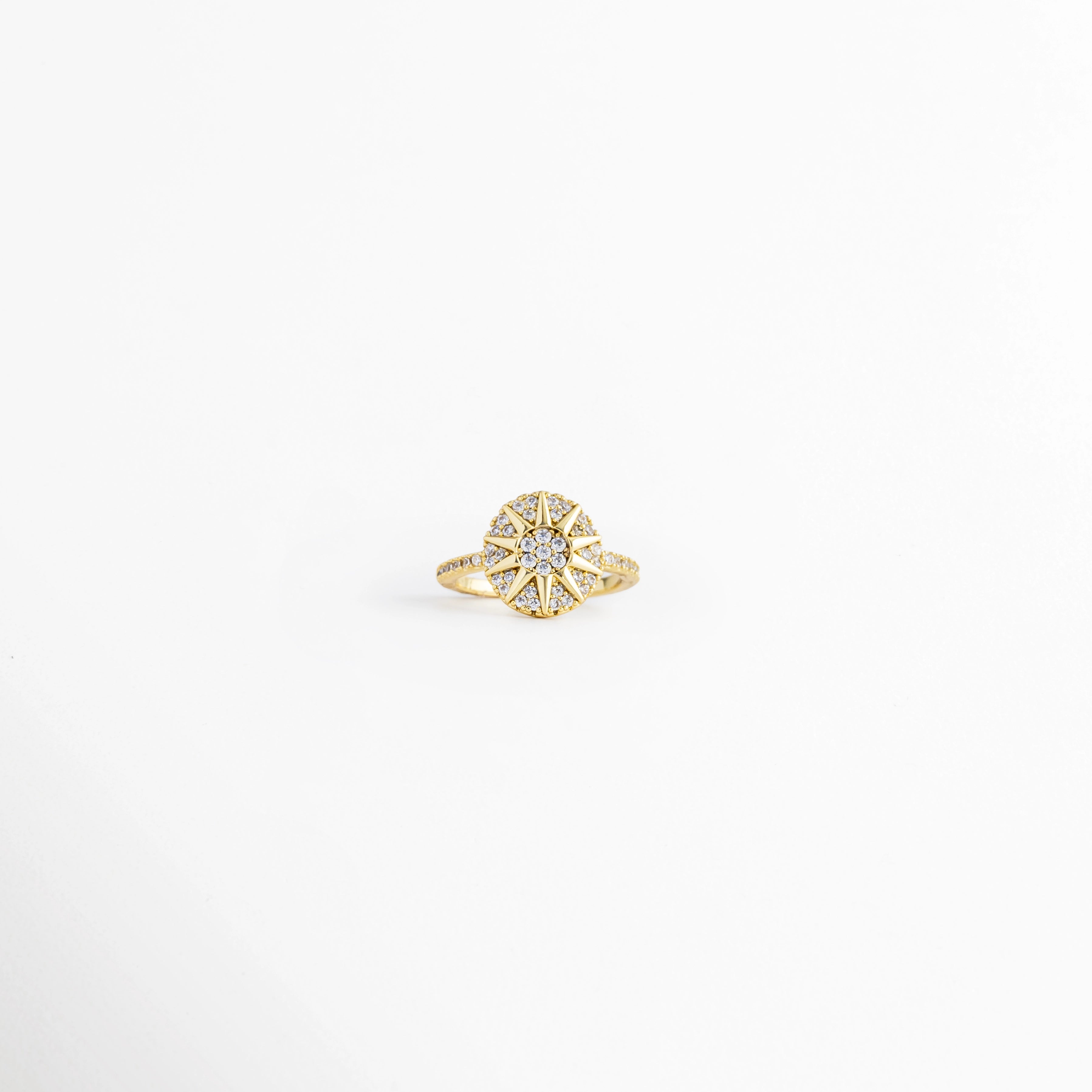 Anillo Elian ajustable de cobre con recubrimiento metálico e incrustaciones de zirconia, diseño floral, vista frontal, Anillo Elian con flor de zirconias y acabado dorado, vista frontal sobre fondo blanco, Vista frontal del Anillo Elian con diseño de flor y zirconia central, Anillo ajustable con motivo floral e incrustaciones de zirconia, vista frontal, Anillo Elian de cobre con acabado metálico brillante y diseño de flor.