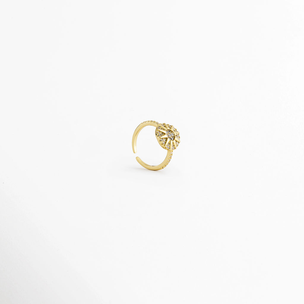 Vista en ángulo del Anillo Elian con diseño floral ajustable, Perspectiva del Anillo Elian que muestra su estructura abierta y ajustable, Vista diagonal del Anillo Elian con flor de zirconias y acabado metálico, Detalle del diseño ajustable del Anillo Elian visto en perspectiva, Anillo Elian en vista lateral diagonal que resalta el brillo de las zirconias.