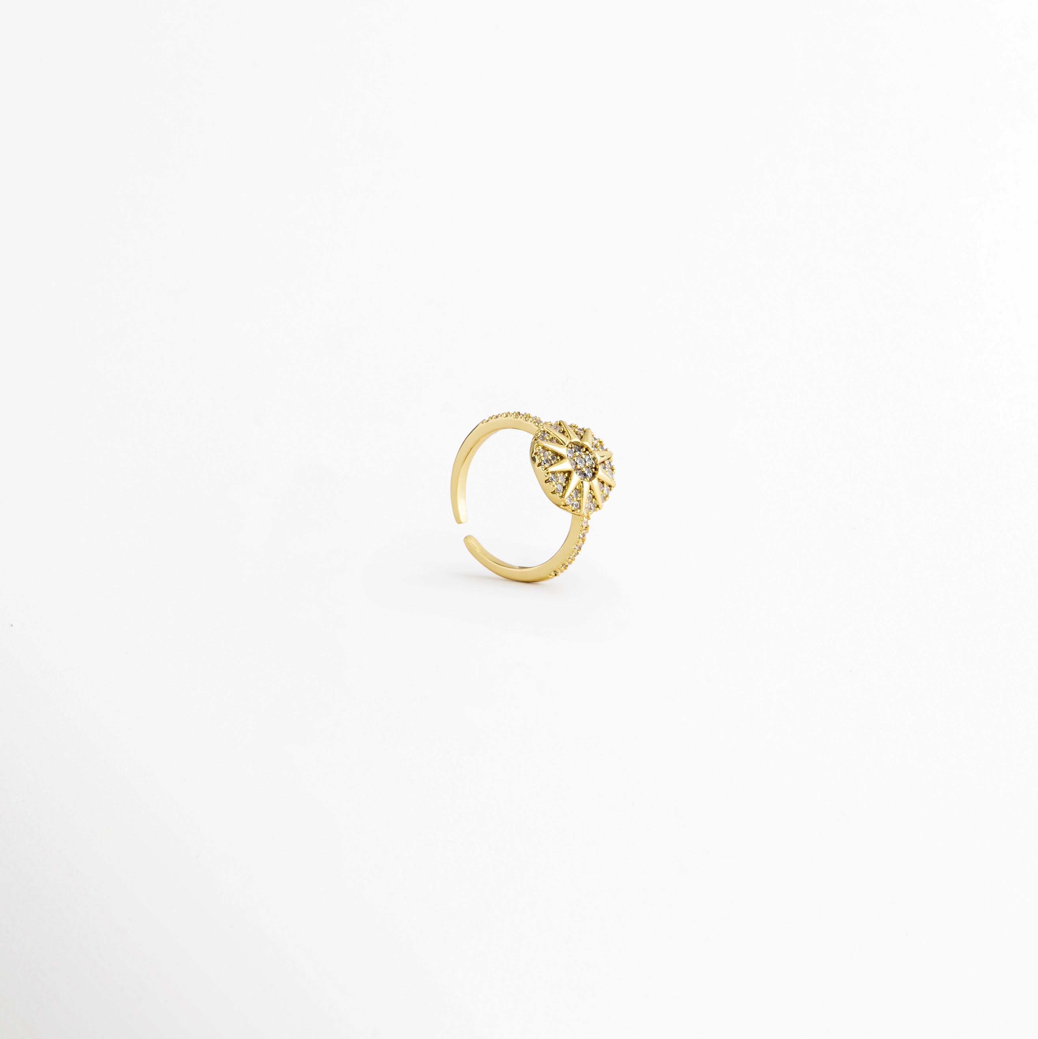 Vista en ángulo del Anillo Elian con diseño floral ajustable, Perspectiva del Anillo Elian que muestra su estructura abierta y ajustable, Vista diagonal del Anillo Elian con flor de zirconias y acabado metálico, Detalle del diseño ajustable del Anillo Elian visto en perspectiva, Anillo Elian en vista lateral diagonal que resalta el brillo de las zirconias.