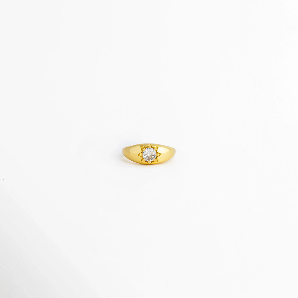 Anillo Sirius ajustable de cobre con recubrimiento pulido brillante y zirconia central, vista frontal, Anillo dorado Sirius con zirconia central y acabado brillante, vista frontal sobre fondo blanco, Vista frontal del Anillo Sirius con diseño minimalista y piedra de zirconia, Anillo ajustable para mujer con zirconia central y acabado dorado brillante, Anillo Sirius de cobre con incrustación de zirconia, vista frontal.