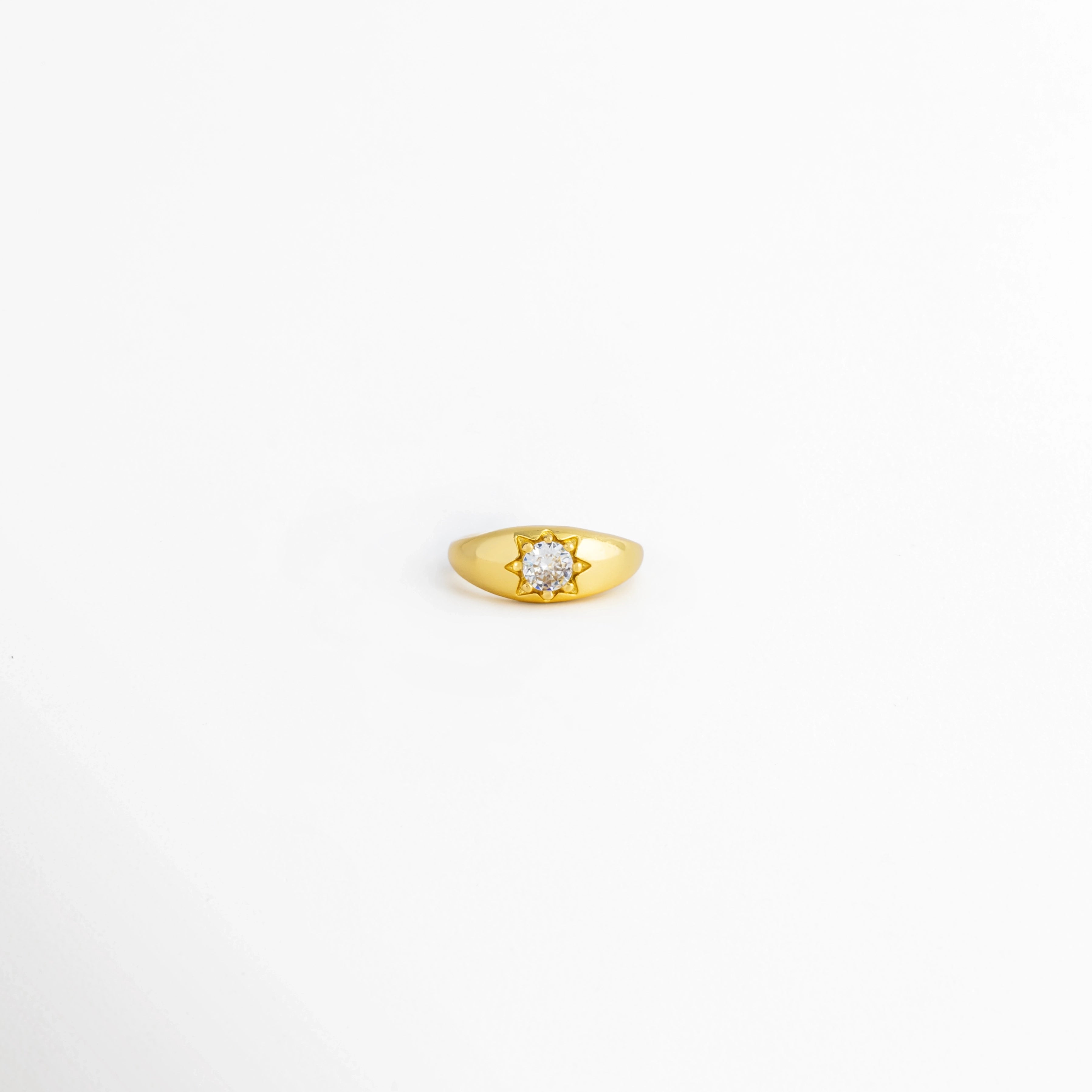 Anillo Sirius ajustable de cobre con recubrimiento pulido brillante y zirconia central, vista frontal, Anillo dorado Sirius con zirconia central y acabado brillante, vista frontal sobre fondo blanco, Vista frontal del Anillo Sirius con diseño minimalista y piedra de zirconia, Anillo ajustable para mujer con zirconia central y acabado dorado brillante, Anillo Sirius de cobre con incrustación de zirconia, vista frontal.
