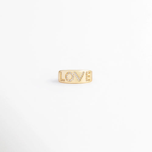 Anillo ajustable de enchapado en oro de 18K con la palabra "LOVE" incrustada en circonias brillantes, vista frontal detallada, Detalle de anillo de cobre enchapado en oro con la palabra "LOVE" formada por circonias, sobre fondo blanco limpio, Vista frontal de anillo ajustable con incrustaciones de piedra circonia sobre fondo claro, Anillo de banda ancha dorado con diseño de "LOVE" en pavé de circonias, perfecto para regalos y uso diario, Plano medio de anillo de bisutería fina ajustable en oro. 