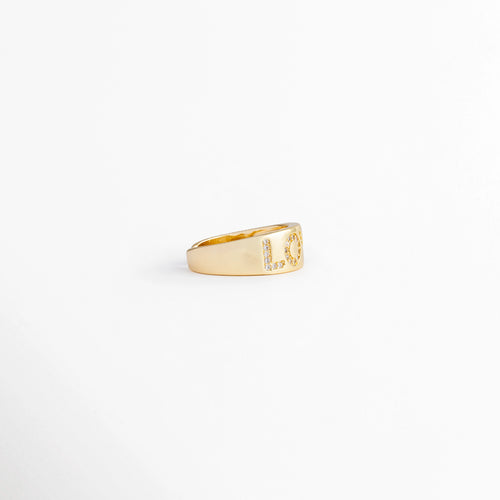 Vista de perfil lateral de anillo "LOVE" en oro 18K, mostrando el grosor de la banda y el inicio del diseño de letras, Ángulo lateral de anillo ajustable de cobre chapado en oro, destacando el acabado pulido y el volumen de la banda, Perspectiva de tres cuartos de anillo "LOVE" con circonias, mostrando la curvatura del diseño sobre fondo blanco, Primer plano de perfil de anillo dorado ajustable con detalle de las letras "L" u "O" iniciales en circonias.