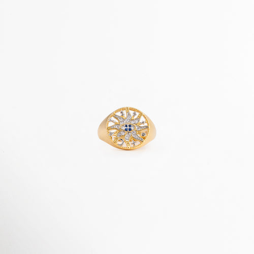 Anillo Alaric dorado tipo sello con diseño calado de sol y zirconias, Anillo ajustable chapado en oro de 14K con patrón místico de estrella brillante, Joyería fina para mujer: anillo dorado con pedrería fina y centro azul sobre fondo blanco, Vista frontal de anillo místico con zirconias incrustadas y detalles calados, Anillo de cobre bañado en oro con diseño celestial redondo y brillante.