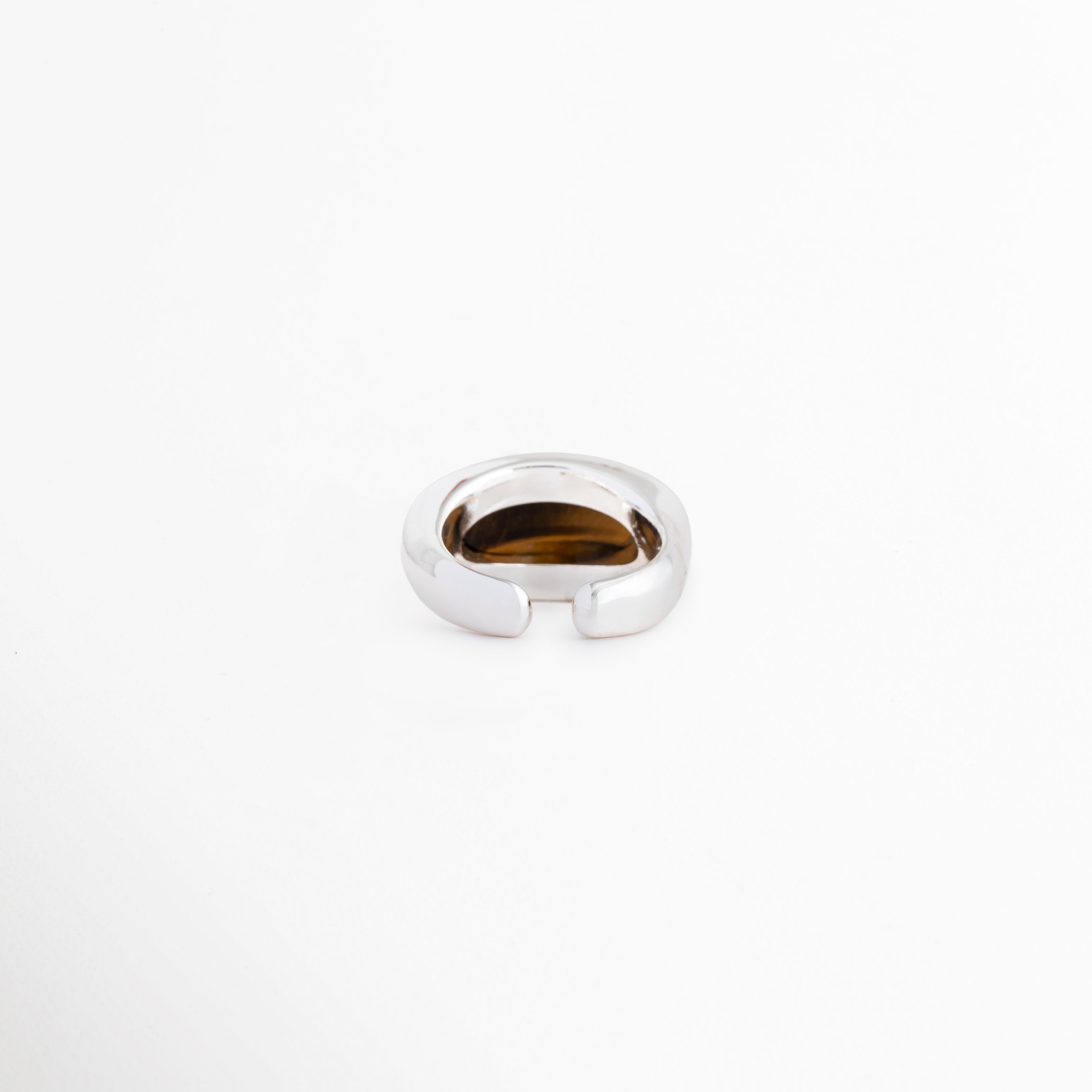 Detalle de la parte posterior abierta del anillo Kaio que permite ajustar la talla, Vista inferior de la banda del anillo ajustable chapado en oro blanco, Sistema de apertura regulable del anillo de cobre para adaptarse a cualquier dedo, Primer plano del diseño abierto y ergonómico del anillo plateado de mujer, Terminación de la banda ajustable del anillo con recubrimiento de oro blanco.