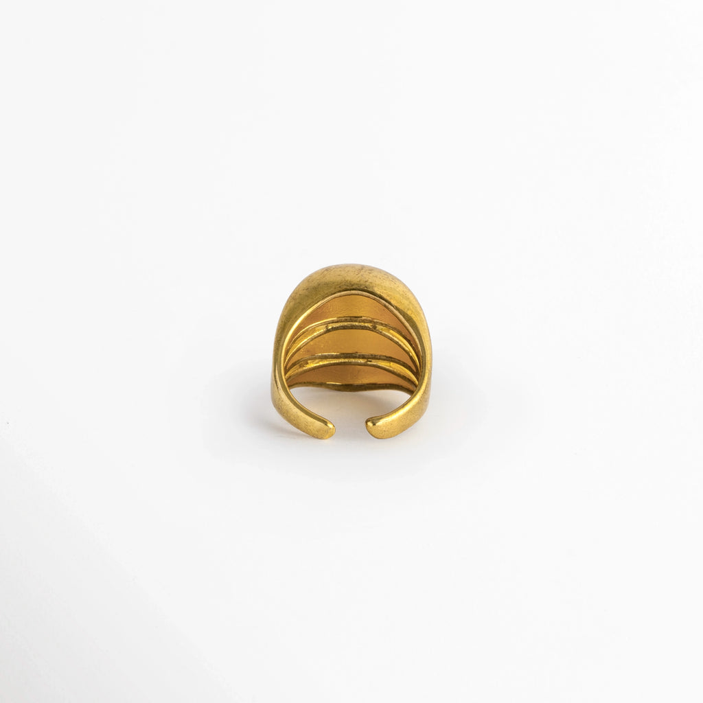  Vista de la cara posterior del Anillo Cass mostrando la abertura inferior ajustable que permite graduar el tamaño, Acercamiento al reverso del anillo dorado abierto con bordes redondeados y suaves para un ajuste cómodo, Toma posterior que muestra la cavidad interna pulida y el sistema adaptable del anillo,  Muestra de la flexibilidad de la caña de cobre enchapada en oro para adaptarse a distintas medidas de dedo. 