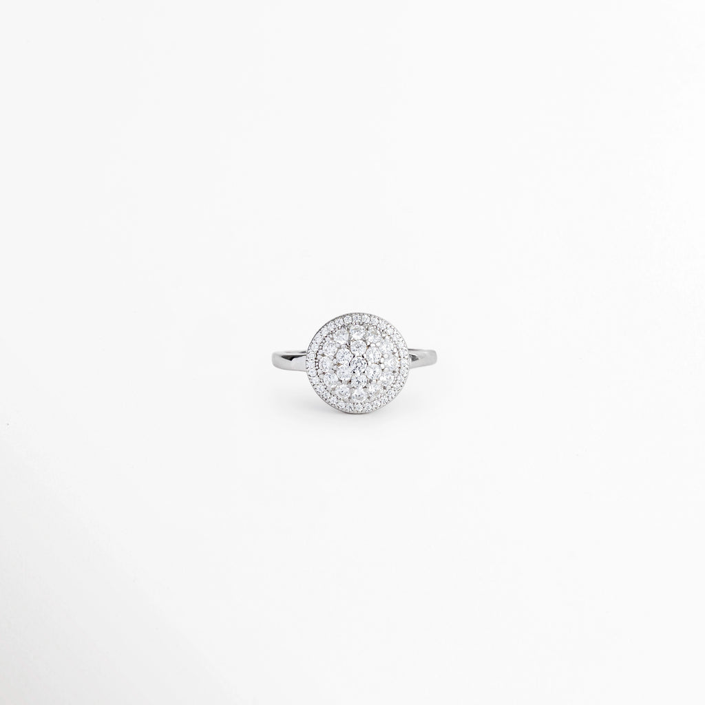 Anillo Tarsila de Plata Ley 925 con diseño de rosetón circular halo cuajado de circonias transparentes, vista frontal sobre fondo blanco, Anillo plateado de plata 925 con gran medallón circular central cubierto de pavé de circonias y aro delgado, Vista de frente de anillo estilo rosetón vintage en plata brillante con aureola o halo de microcirconias, Anillo de cóctel de 1.8 cm en plata con cúmulo de circonias cristalinas formando un disco luminoso.