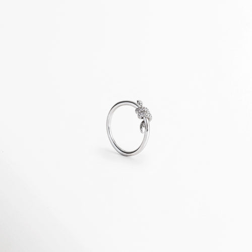Anillo Node en ángulo de tres cuartos mostrando la textura del nudo de 0.5 cm y el destello de las circonias, Vista inclinada de anillo delgado plateado con nudo orgánico enchapado en oro blanco 18K, Anillo de promesa fino en perspectiva diagonal exhibiendo la tridimensionalidad del nudo, Toma en ángulo de tres cuartos de anillo minimalista plateado con incrustaciones de pedrería.