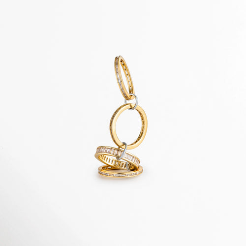 Anillo Leonora desplegado verticalmente mostrando la unión de aros entrelazados mediante argollas metálicas, Vista lateral en equilibrio de aros dorados delgados con circonias unidos en cadena articulada, Estructura interactiva y articulada del anillo de aros múltiples dorados con circonias transparentes, Detalle del mecanismo de conexión entre los aros finos enchapados en oro 18K sobre superficie blanca.