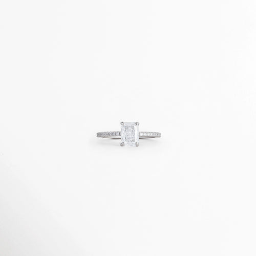 Anillo de compromiso de plata con gema central de circonia corte rectangular esmeralda o radiante y engaste de cuatro uñas, vista frontal sobre fondo blanco, Anillo solitario plateado enchapado en oro blanco de 0.8 x 0.6 cm con circonia rectangular y banda delgada engastada, vista de frente de anillo de promesa en plata con piedra cristalina rectangular de corte radiante y pavé en los hombros, Anillo de compromiso en tono oro blanco con circonia cúbica rectangular 
