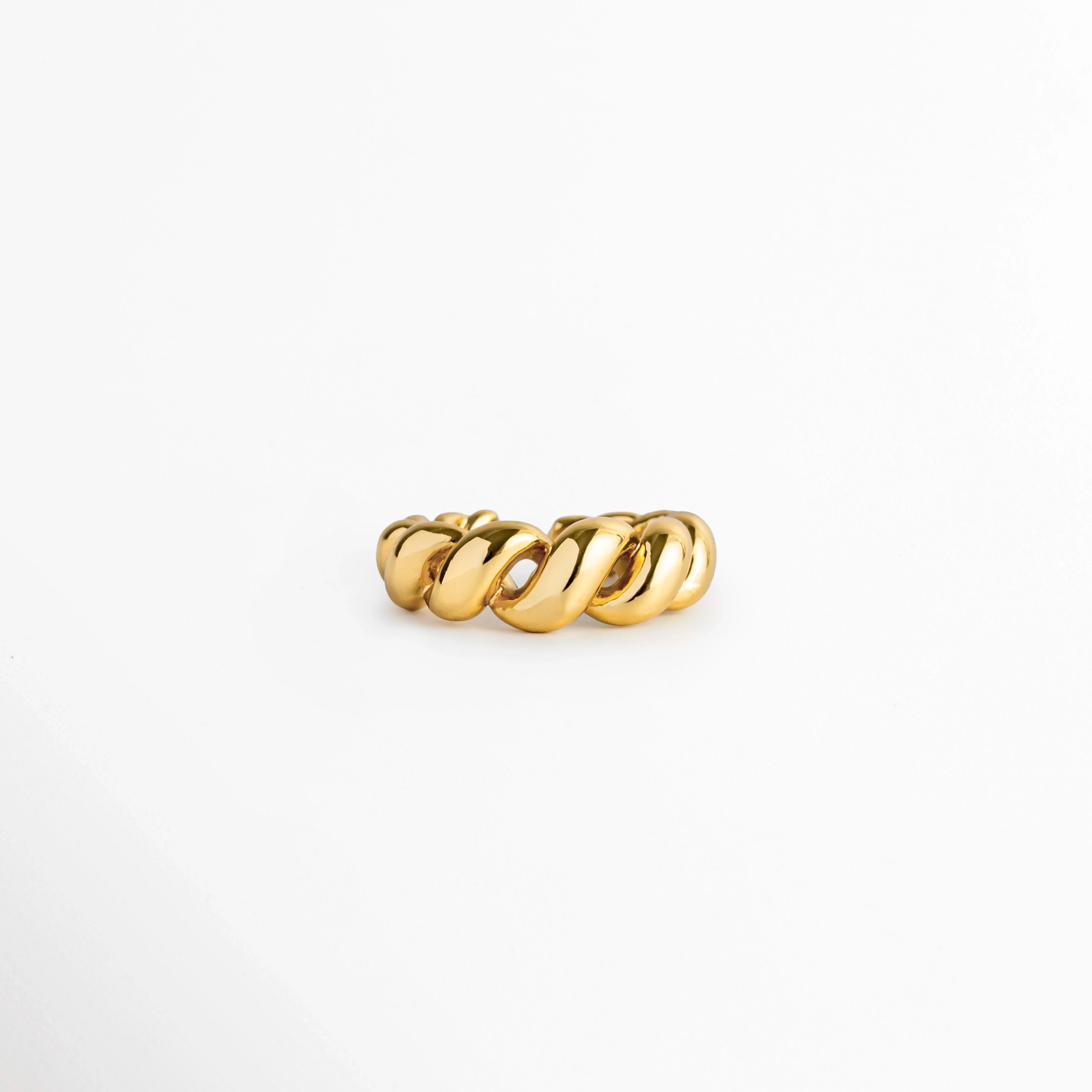 Anillo Olalla Golden en tono oro 24K brillante con diseño retorcido tipo cuerda o cordón, vista frontal sobre fondo blanco, Anillo ajustable de latón enchapado en oro 24K con relieve entrelazado de textura espiral, Vista de frente de anillo abierto con diseño de cordoncillo en relieve abombado sobre superficie neutra, Anillo de textura retorcida en acabado oro de 24 quilates de alto brillo.