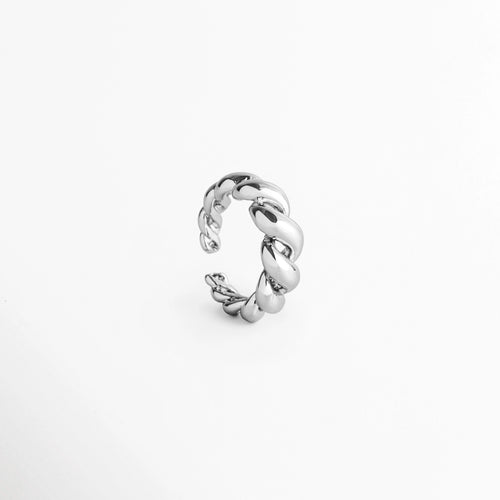 Anillo Olalla Silver en perspectiva de tres cuartos destacando la tridimensionalidad del grabado tipo cuerda y el destello del oro blanco 24K, Vista inclinada de anillo ajustable entrelazado en tono plata con reflejos fríos y pulidos, Anillo plateado con textura de cordón en ángulo de tres cuartos exhibiendo su silueta curva y abierta, Toma en ángulo de anillo de moda ajustable en tono plata brillante sobre superficie clara.