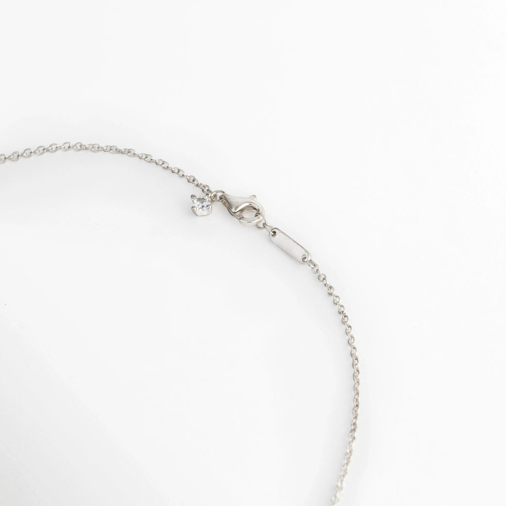 Acercamiento al broche de mosquetón y la cadena de extensión de 10.5 cm enchapada en oro blanco del Collar Palencia, Vista macro del sistema de ajuste seguro con eslabones de extensión y terminación metálica sobre fondo blanco, Detalle de los acabados de la cadena fina de 48 cm con opción de ajuste largo, Muestra del mecanismo de sujeción pulido en tono oro blanco de alta durabilidad.