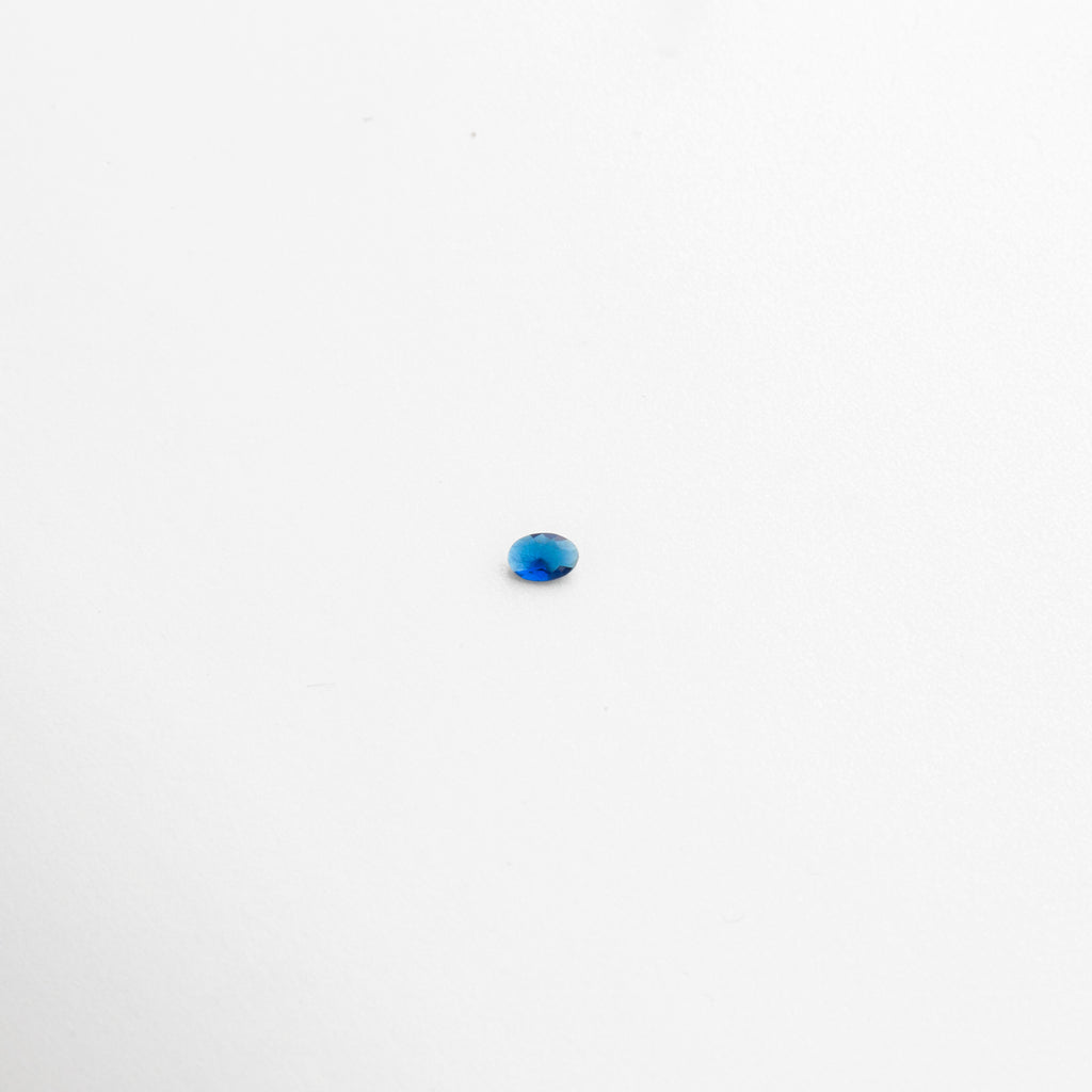 Piedra de cristal ovalada color azul brillante sobre fondo blanco, Cristal pequeño azul intenso con acabado translúcido tipo gema, Piedra artificial de cristal azul en corte ovalado con brillo, Cristal decorativo de 0.6 cm en tono azul con reflejos luminosos, Gema de cristal sintético azul pequeño con acabado pulido