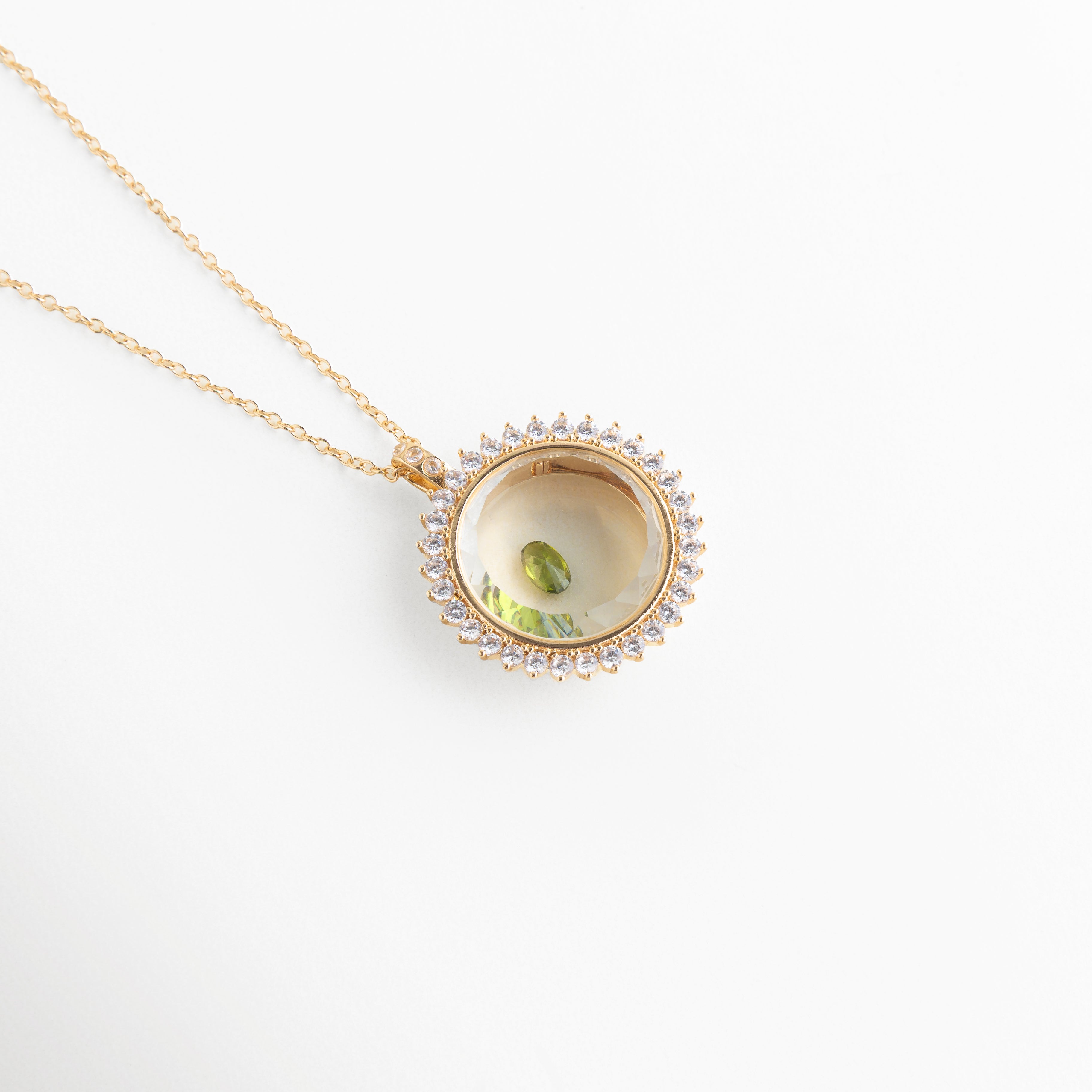 Collar dorado con dije circular y piedra de cristal verde central, Dije elegante con cristal verde brillante en diseño tipo ojo, Joyería fina con piedra verde de cristal en accesorio minimalista, Collar delicado con cristal verde pequeño en acabado brillante, Accesorio de bisutería con gema verde en diseño moderno y fino