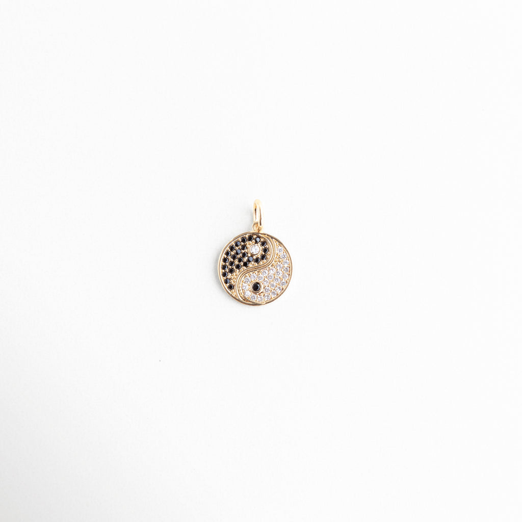 Detalle de dije Yin Yang de 2 cm en oro de 14K con zirconias, Dije redondo Yin Yang con pavé de cristales negros y transparentes, Amuleto circular de equilibrio en chapa de oro de 14K de Amalaya, Primer plano de medalla Yin Yang dorada con pedrería fina de laboratorio, Dije de Yin Yang brillante de 0.5 cm de ancho en fondo blanco