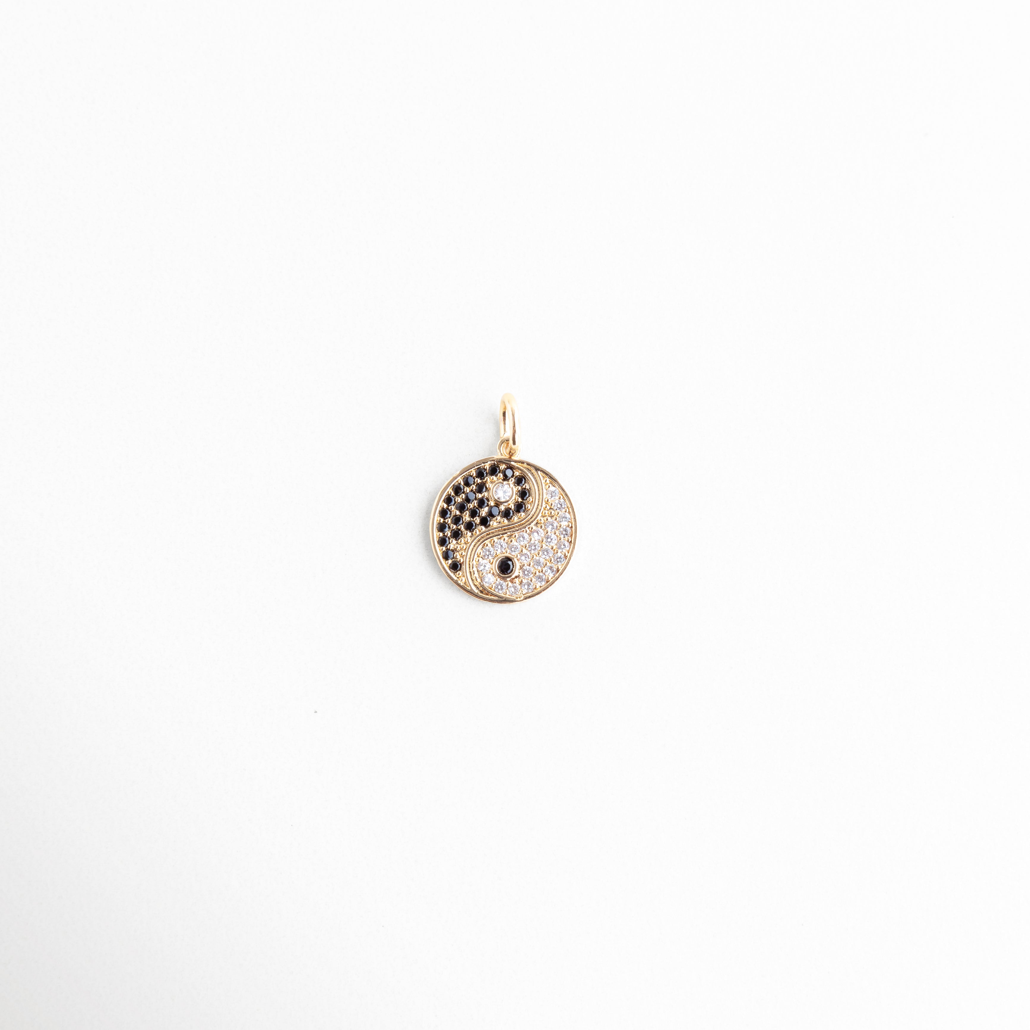 Detalle de dije Yin Yang de 2 cm en oro de 14K con zirconias, Dije redondo Yin Yang con pavé de cristales negros y transparentes, Amuleto circular de equilibrio en chapa de oro de 14K de Amalaya, Primer plano de medalla Yin Yang dorada con pedrería fina de laboratorio, Dije de Yin Yang brillante de 0.5 cm de ancho en fondo blanco