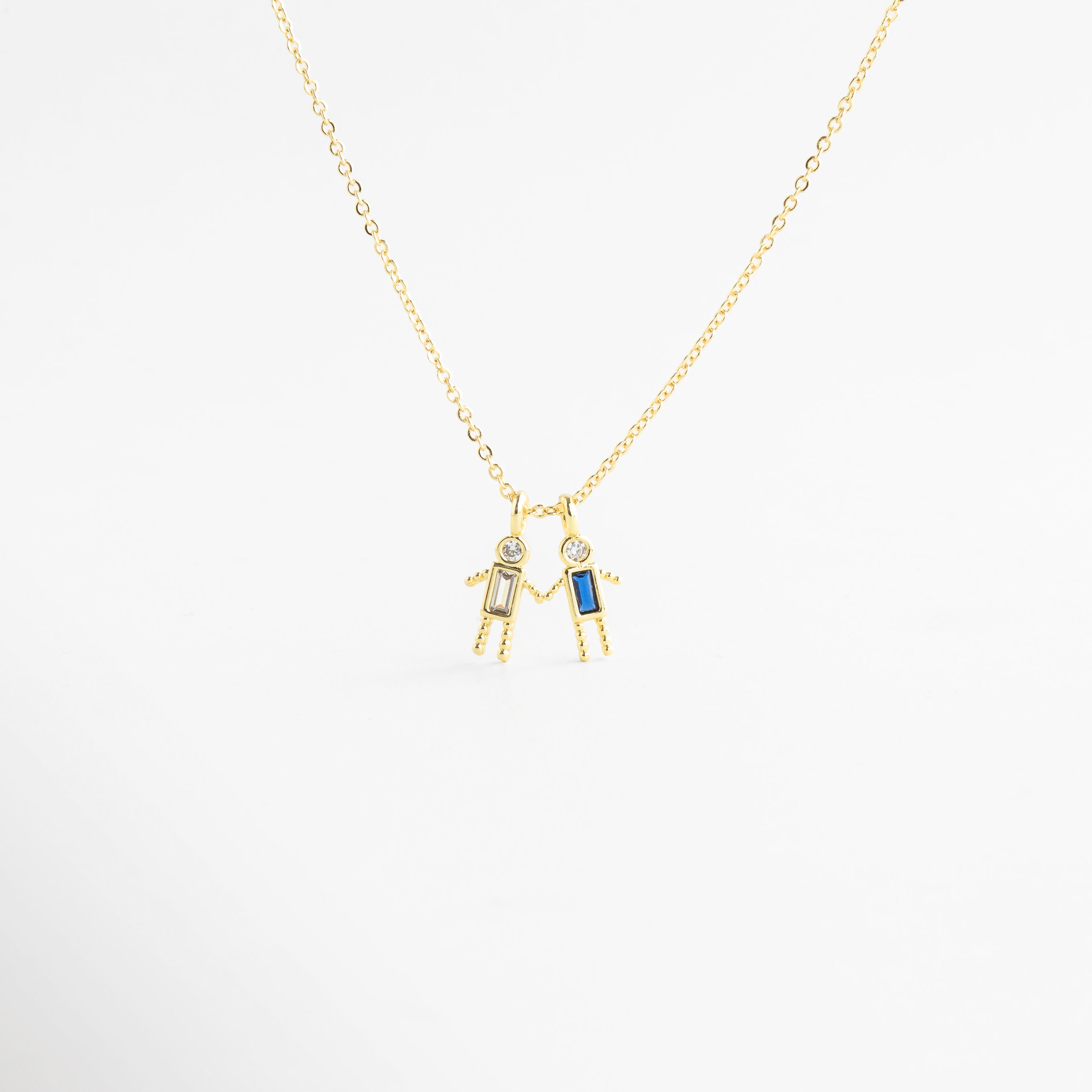 Dije dorado de niño con zirconia azul en diseño delicado, Detalle de colgante con piedra azul y figura masculina minimalista, Collar con dije pequeño de niño y zirconia azul brillante, Colgante en oro 18K con zirconia azul y acabado pulido, Detalle de collar con figura de niño y piedra azul